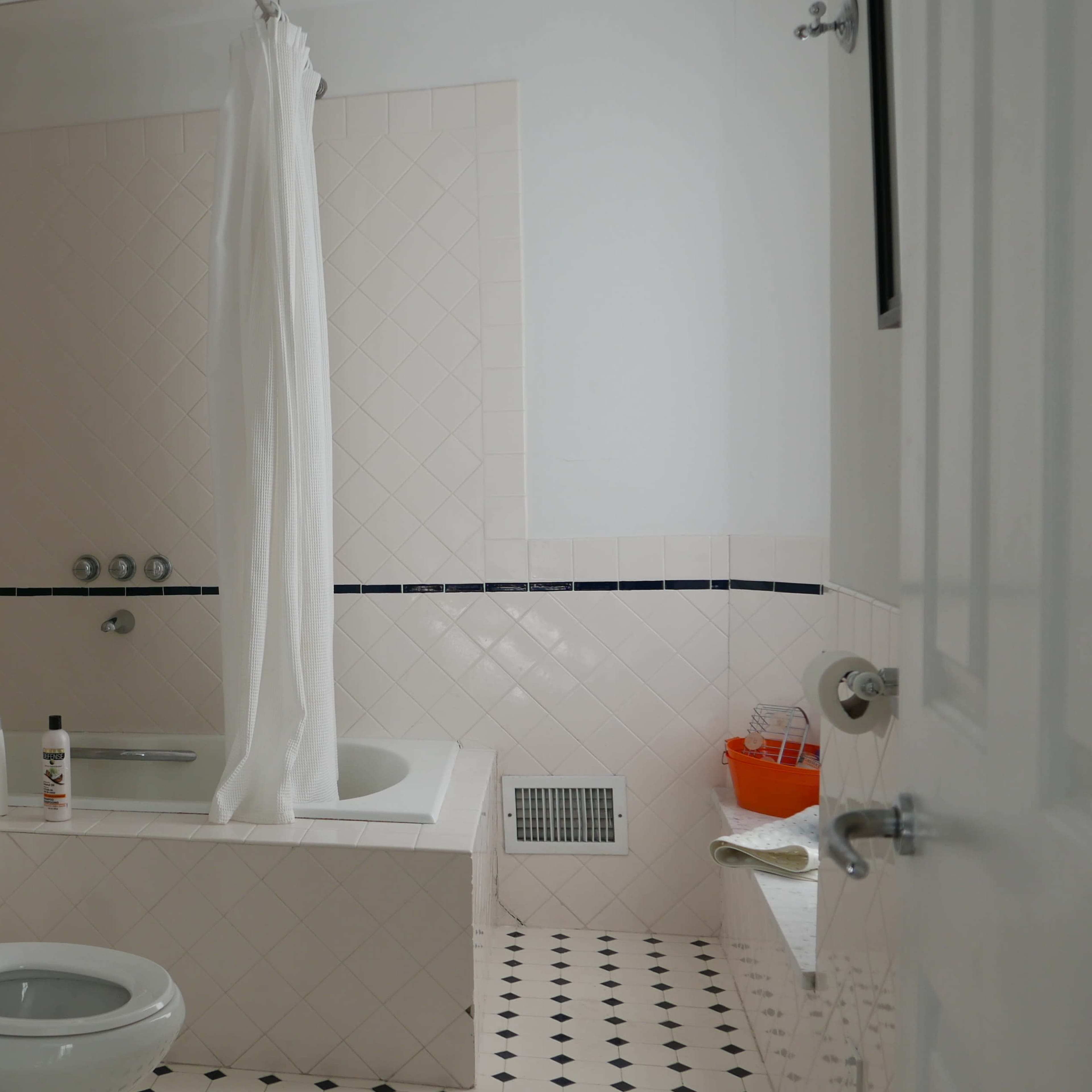 A bathroom with a bathtub, shower curtain, toilet, sink, and tiled floor.