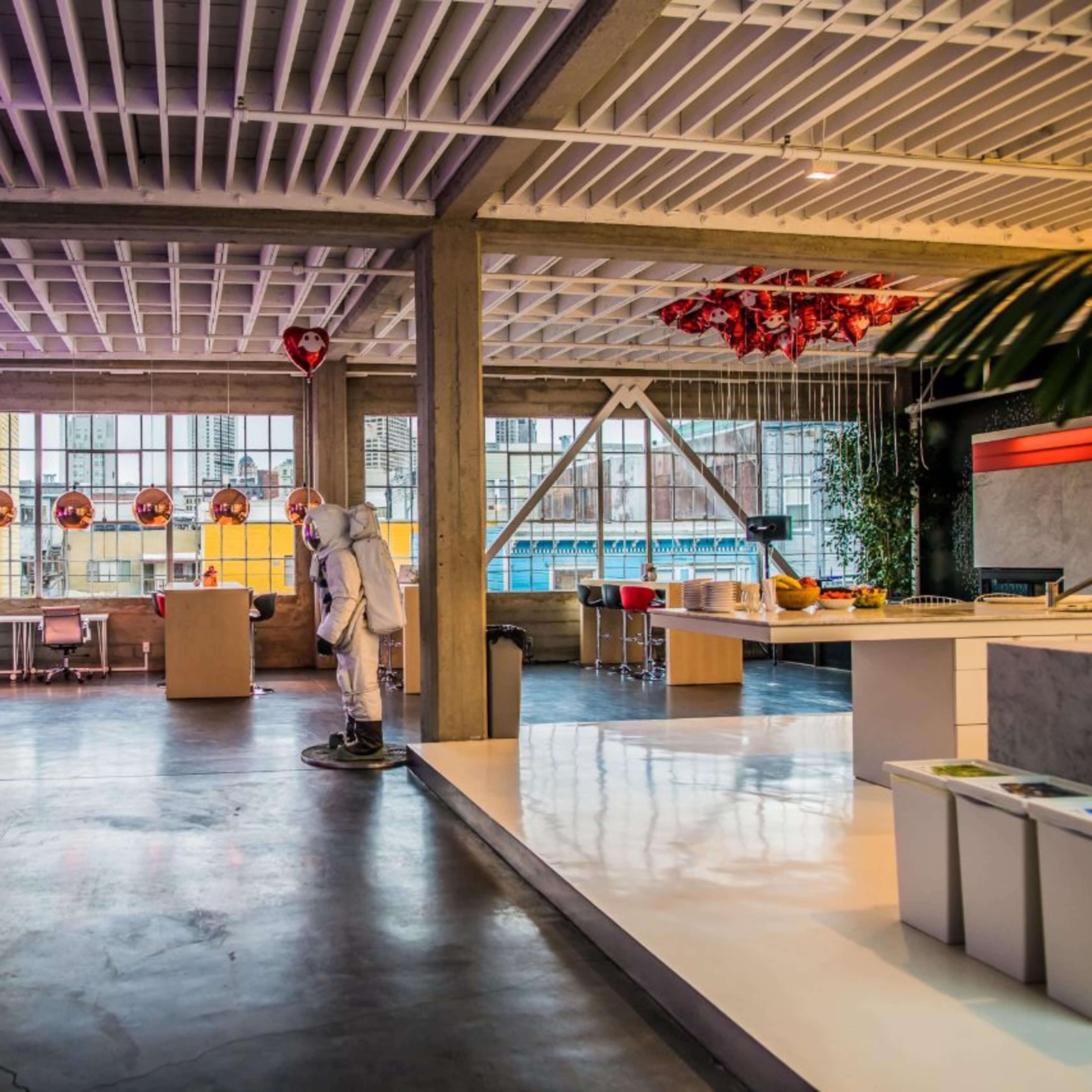 A modern office space with large windows, colorful decorations, and an astronaut figure standing in the foreground.