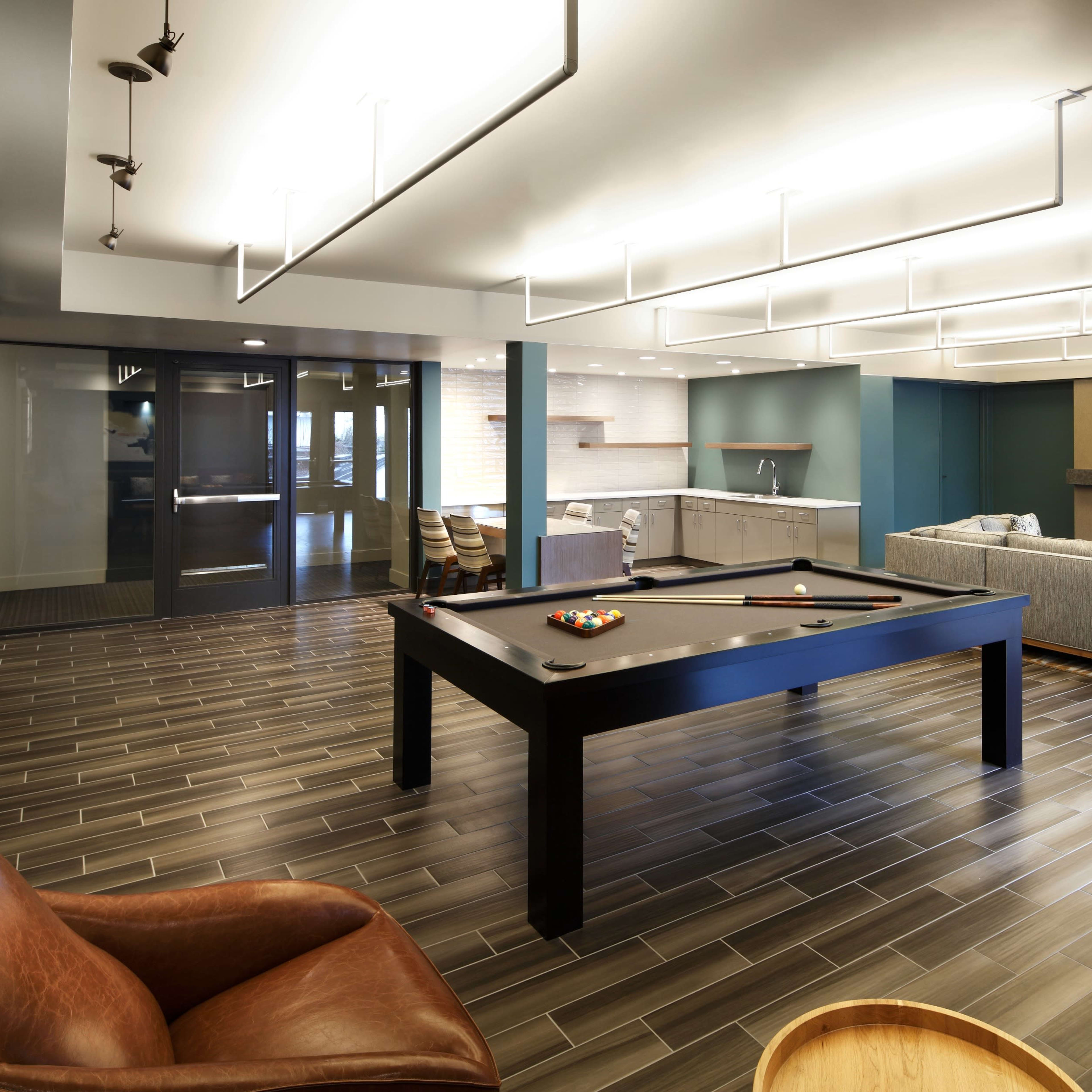 A modern recreational room featuring a pool table, comfortable seating, and a television mounted on the wall.