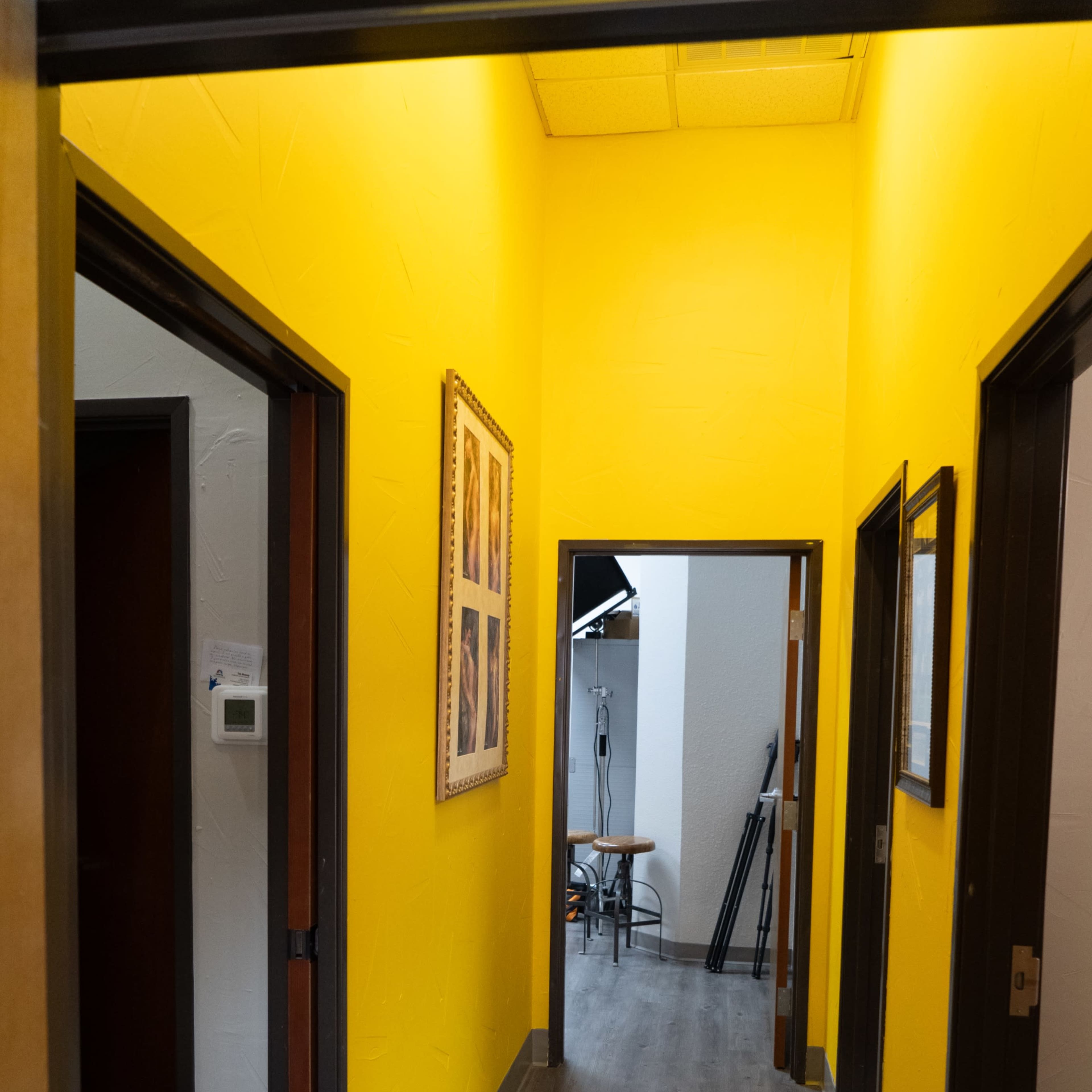 A narrow hallway with yellow walls and wooden doors on either side, leading to another room at the end.