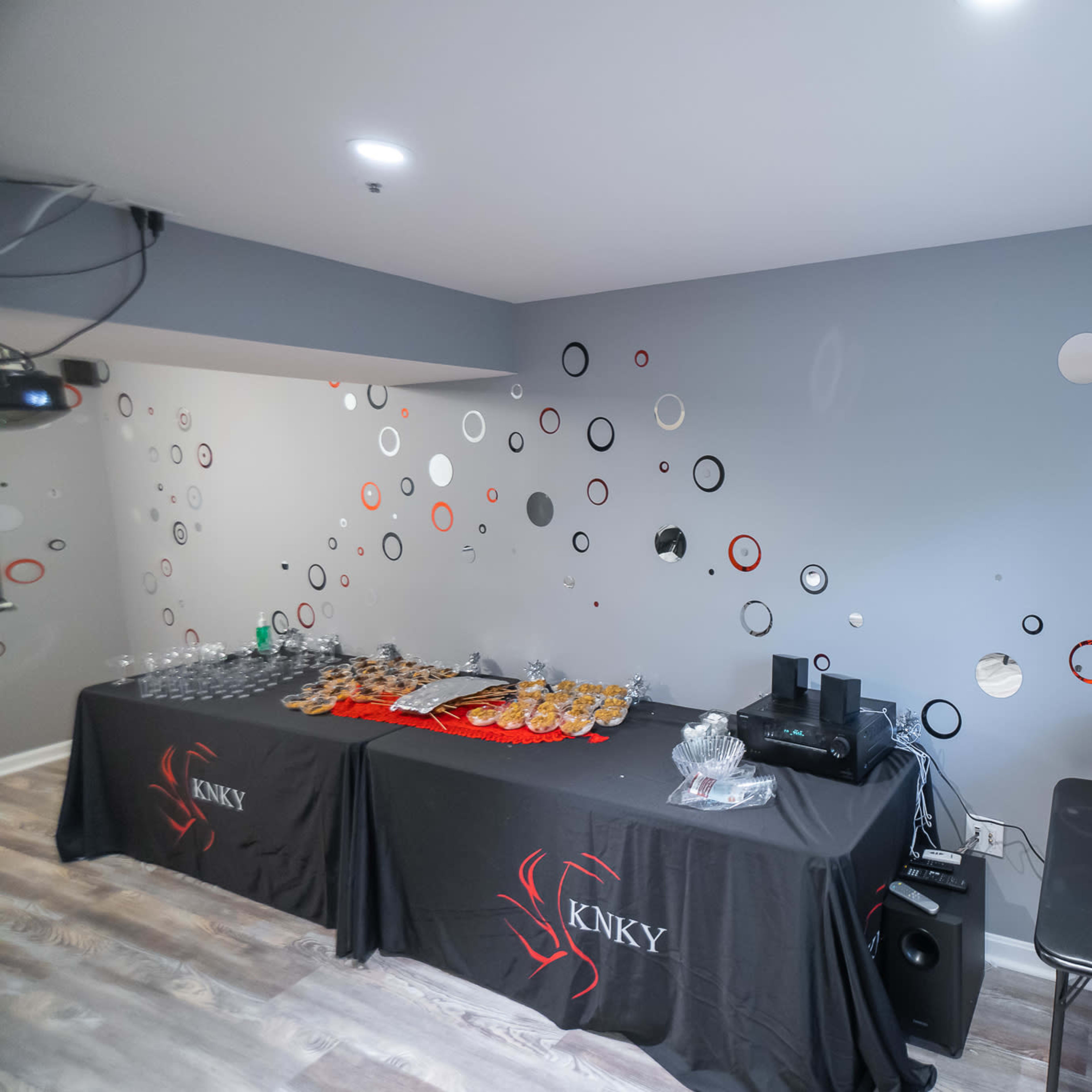 A room with two tables, one displaying various food items and the other with neatly arranged takeout bags, set against a wall decorated with circular wall art.