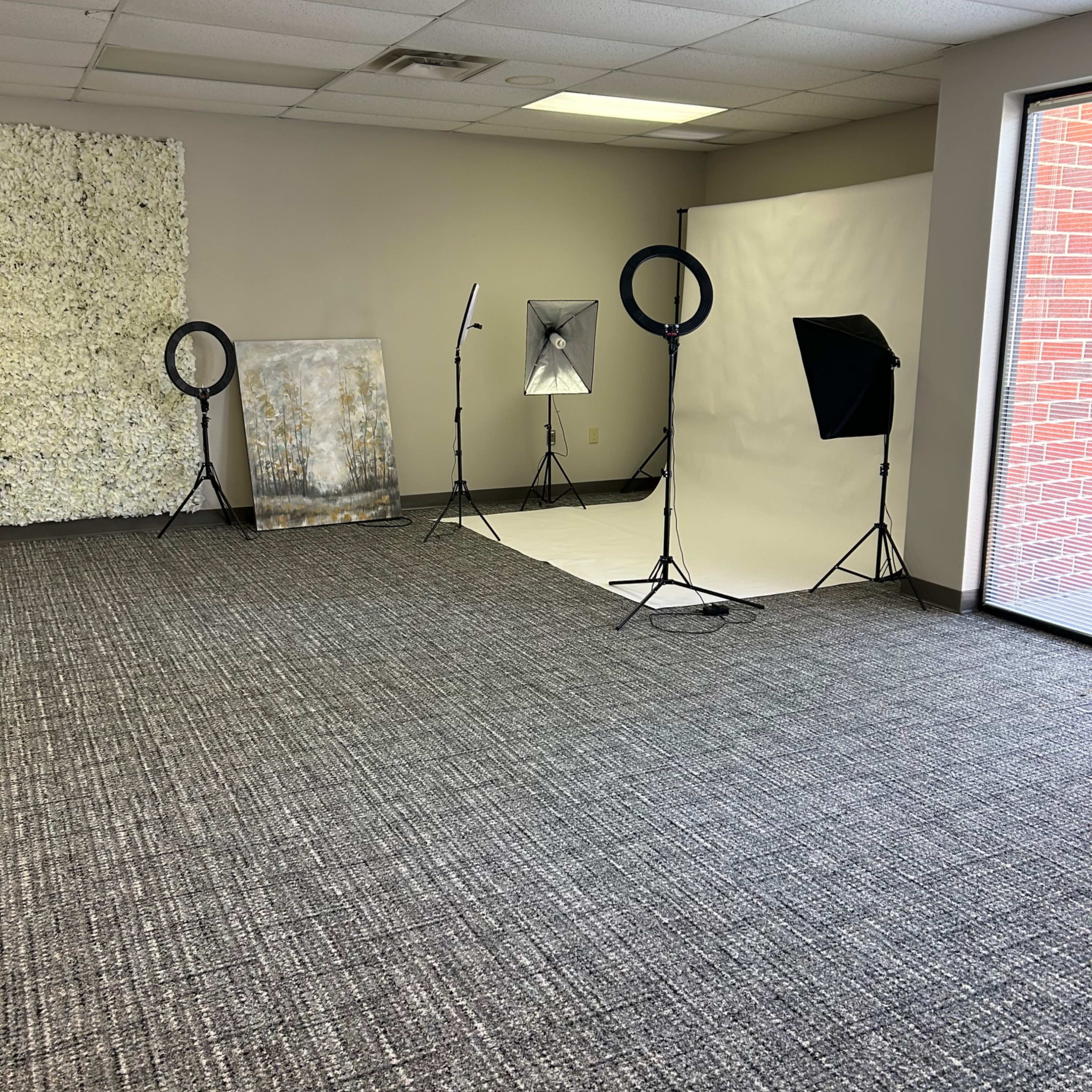 A spacious, empty room equipped with photography lighting setups and a backdrop.