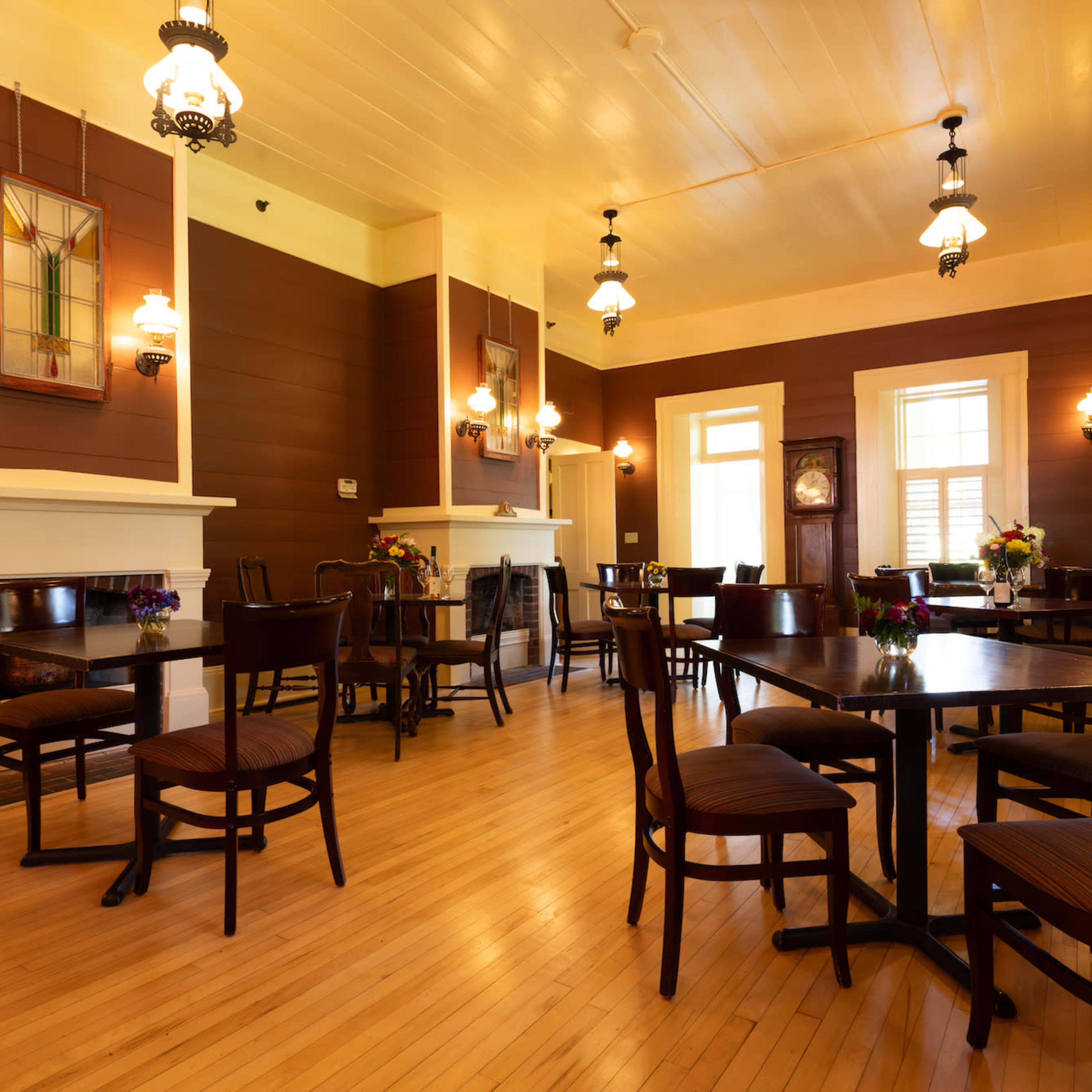 A spacious, warmly lit dining area with wooden tables and chairs arranged around a polished wooden floor.