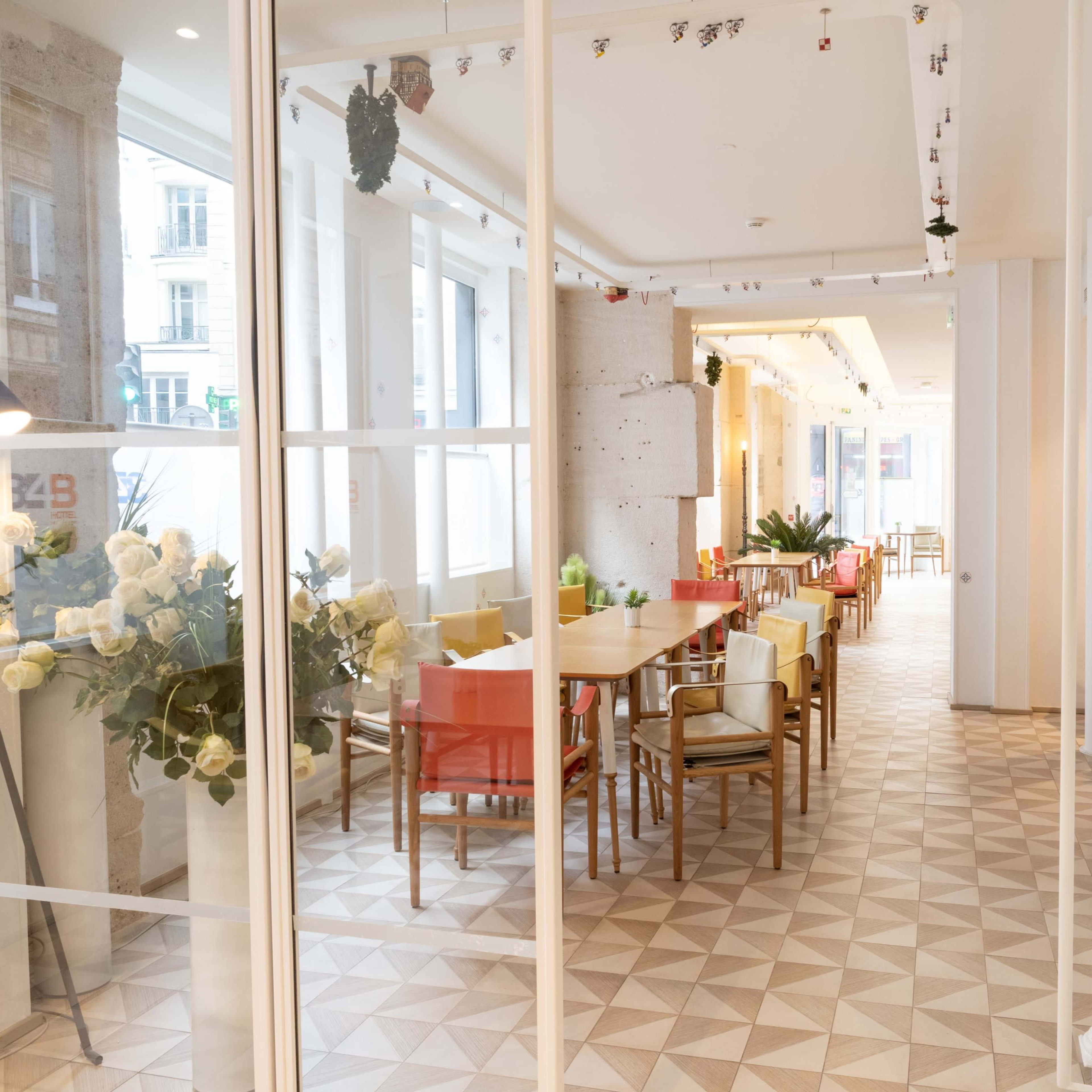 A modern interior space with a dining area featuring wooden tables, colorful chairs, and decorative plants.