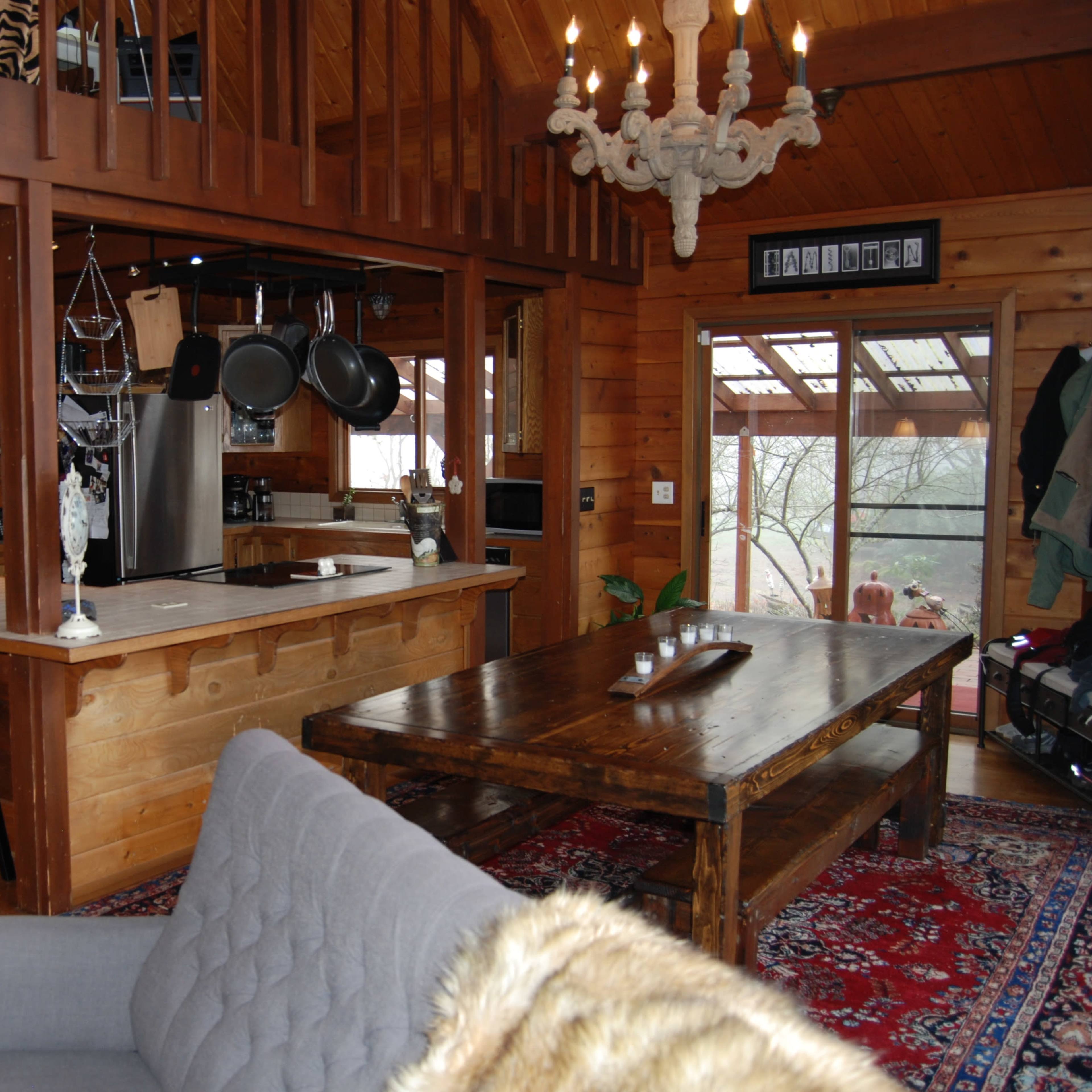A rustic wooden interior of a house with a kitchen area, a large dining table, and a seating area.