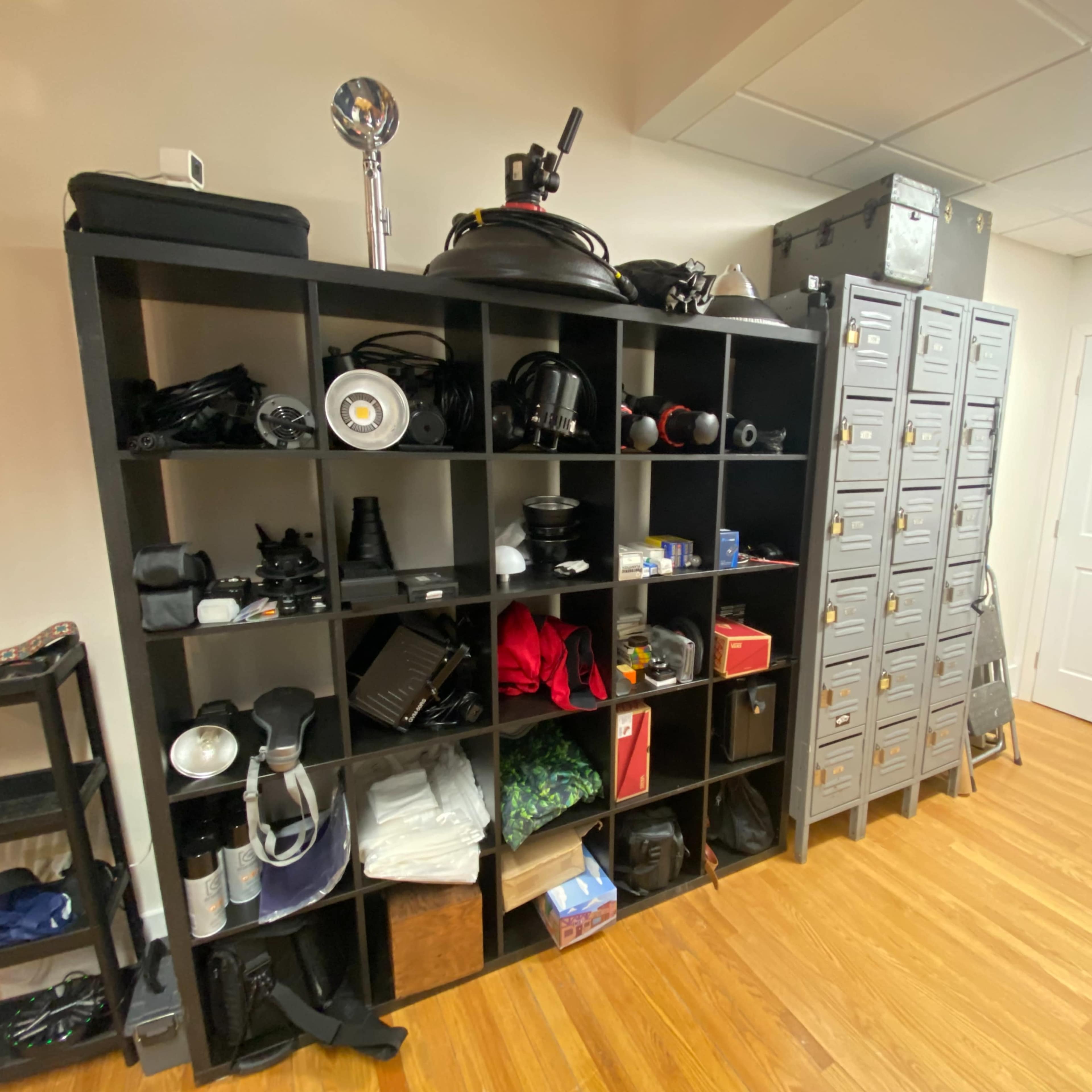 A shelving unit filled with various tools and equipment is displayed against a light-colored wall, next to a door with a clear exit sign.