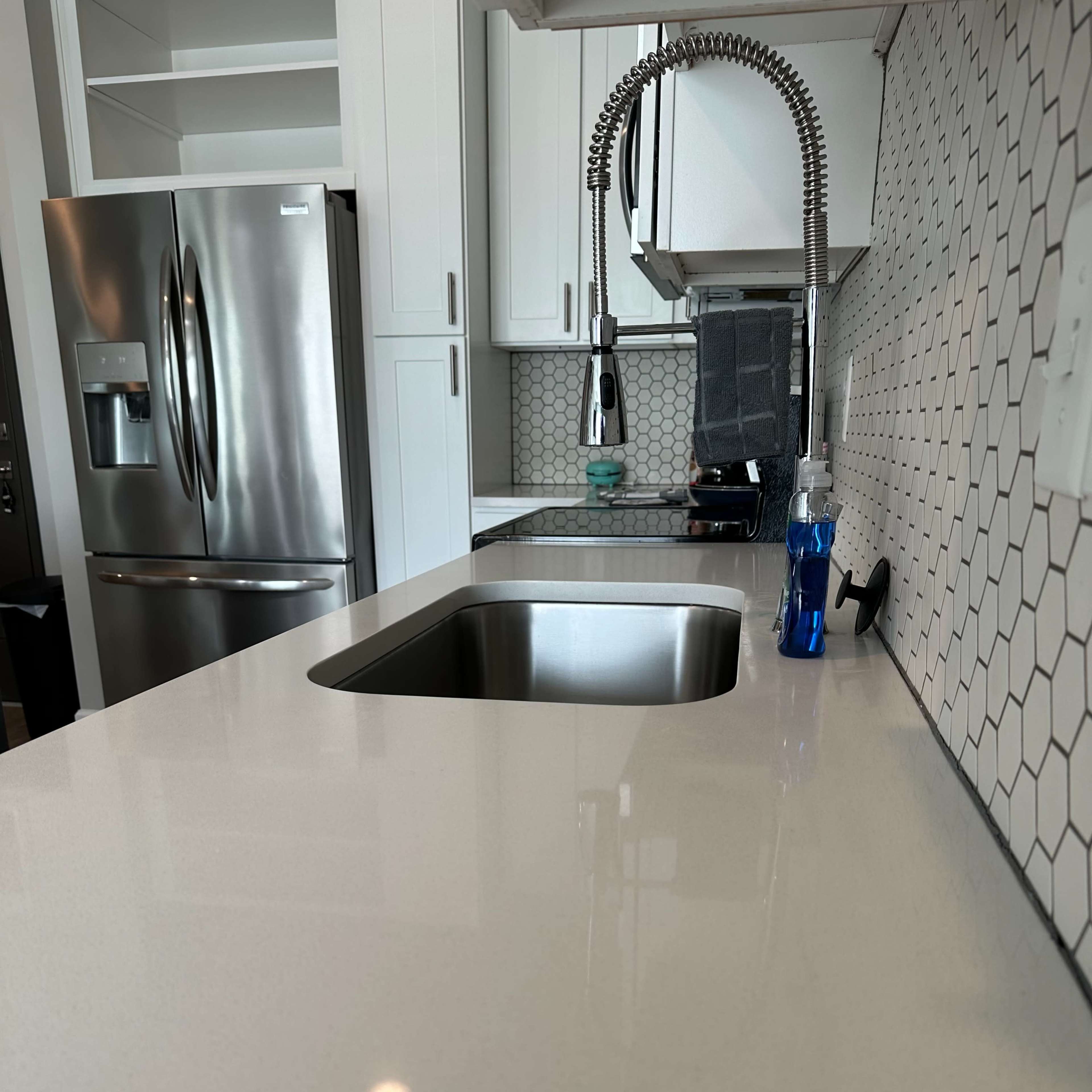 A modern kitchen countertop with a stainless steel sink, a faucet, and a bottle of water beside it.