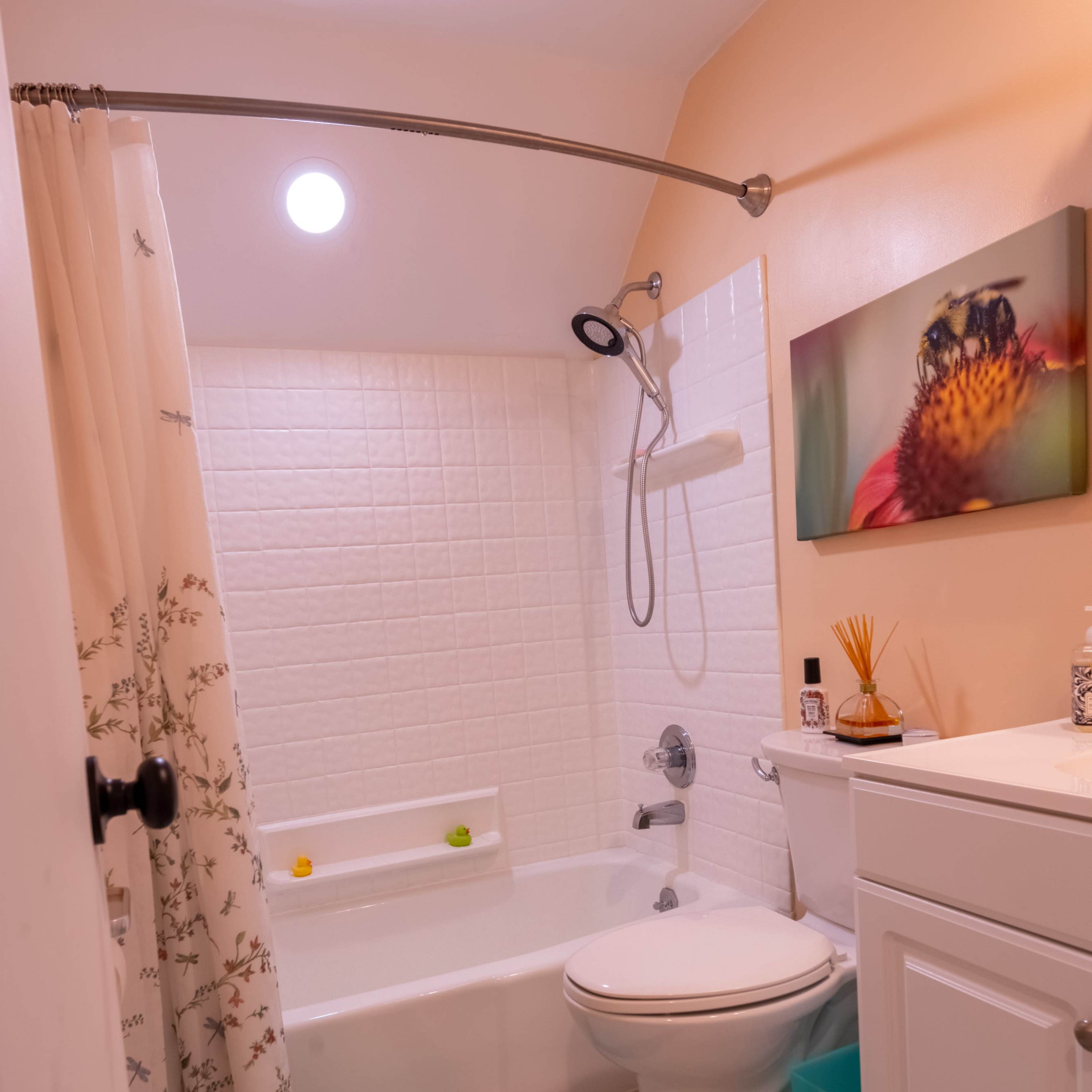 A small bathroom with a bathtub, toilet, sink, and a colorful bath mat.