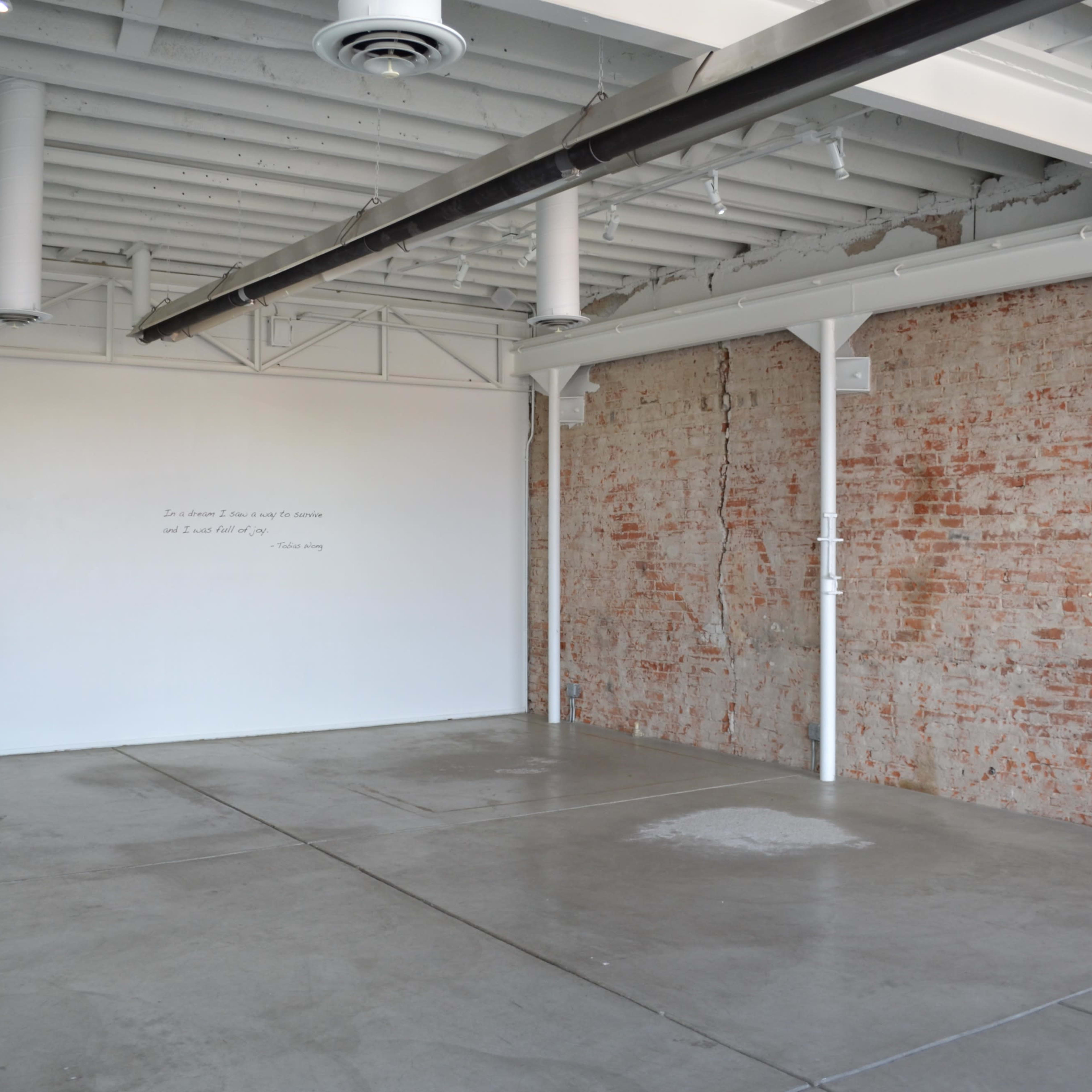 A spacious, minimalist interior with an exposed brick wall and polished concrete flooring.