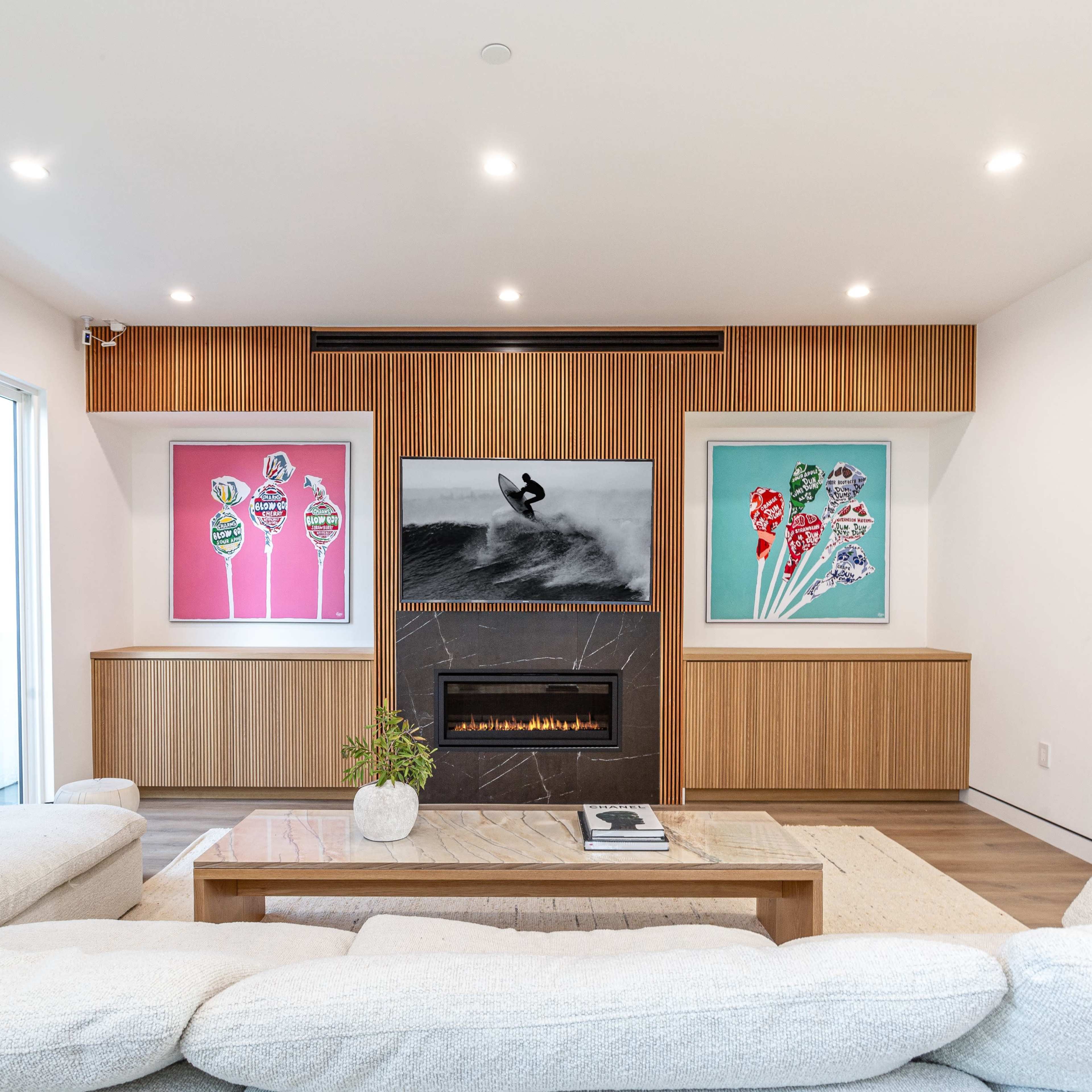 A modern living room features a sectional sofa, a fireplace, and colorful artwork on the walls.
