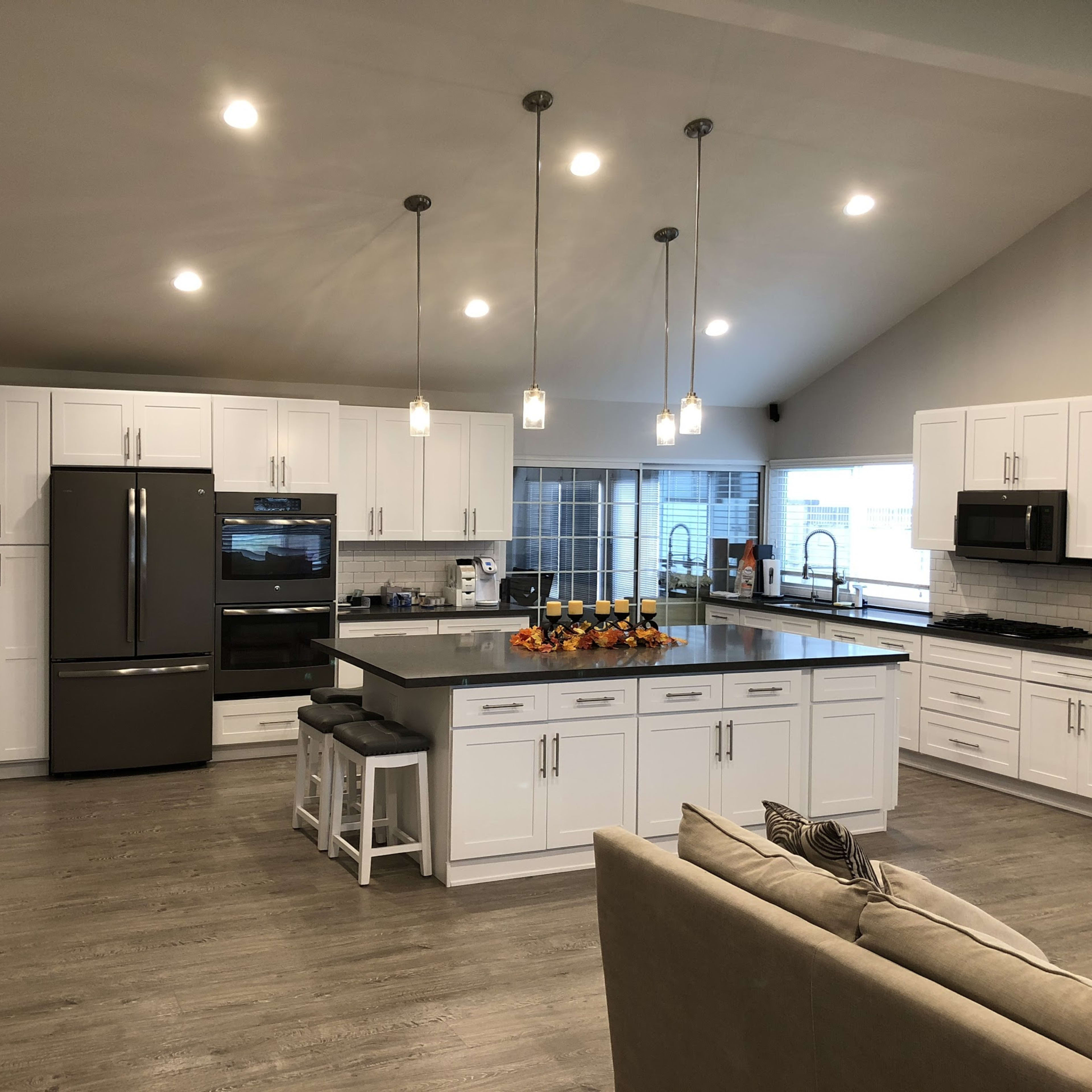 The kitchen features white cabinetry, modern appliances, and a large island with seating.