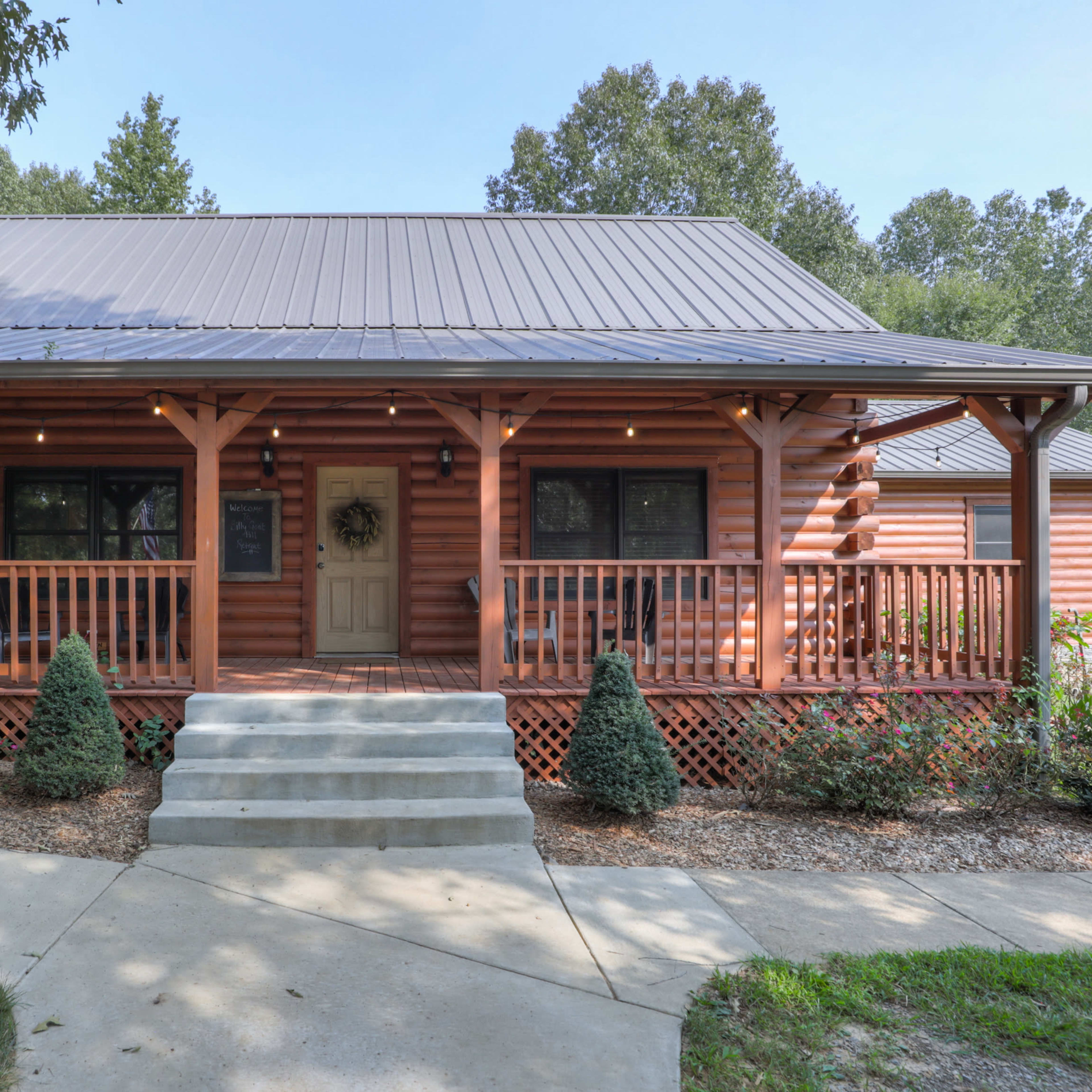 A log cabin with a front porch, steps leading to the door, and an American flag displayed prominently.