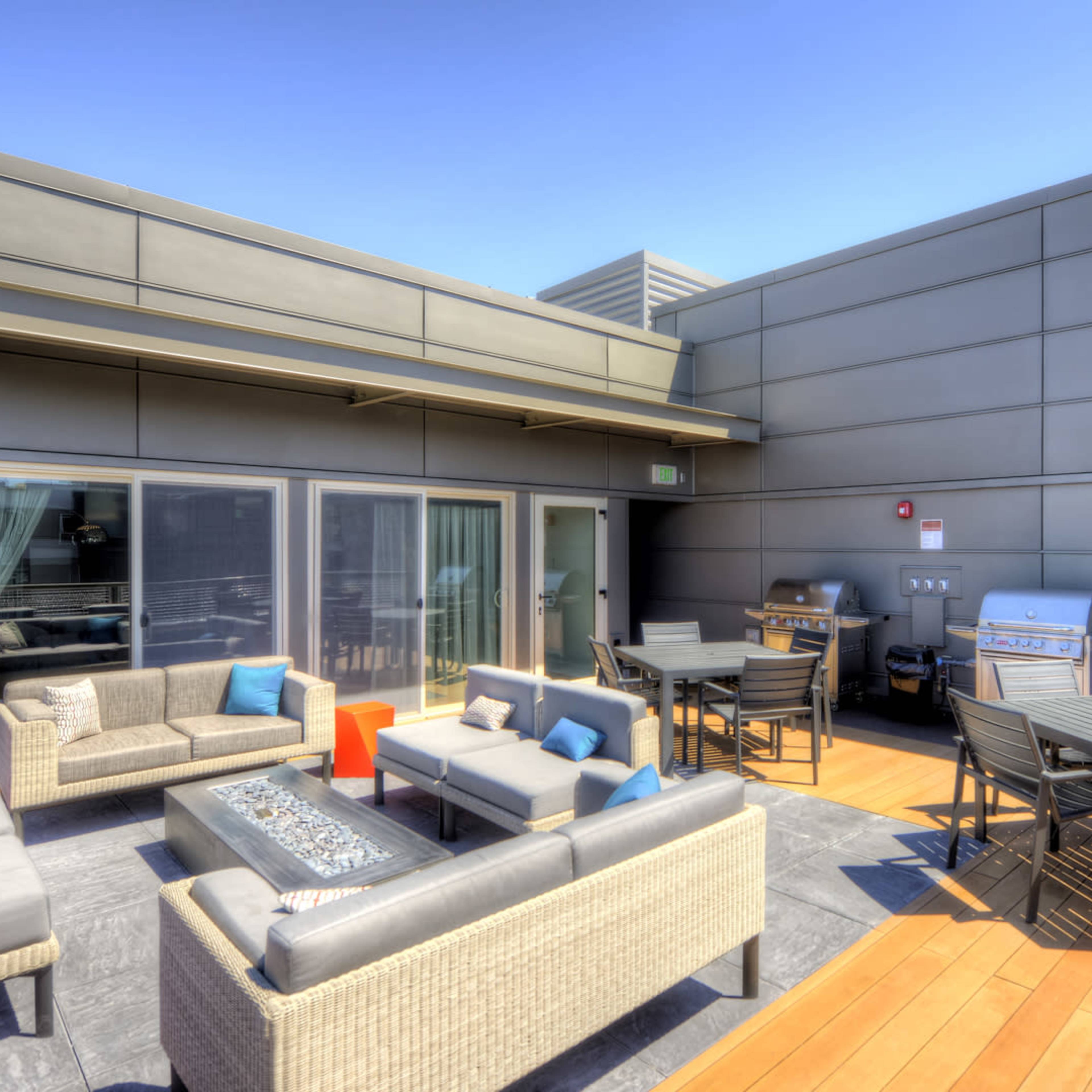 The rooftop terrace features seating arrangements, gas grills, and dining tables with a view.