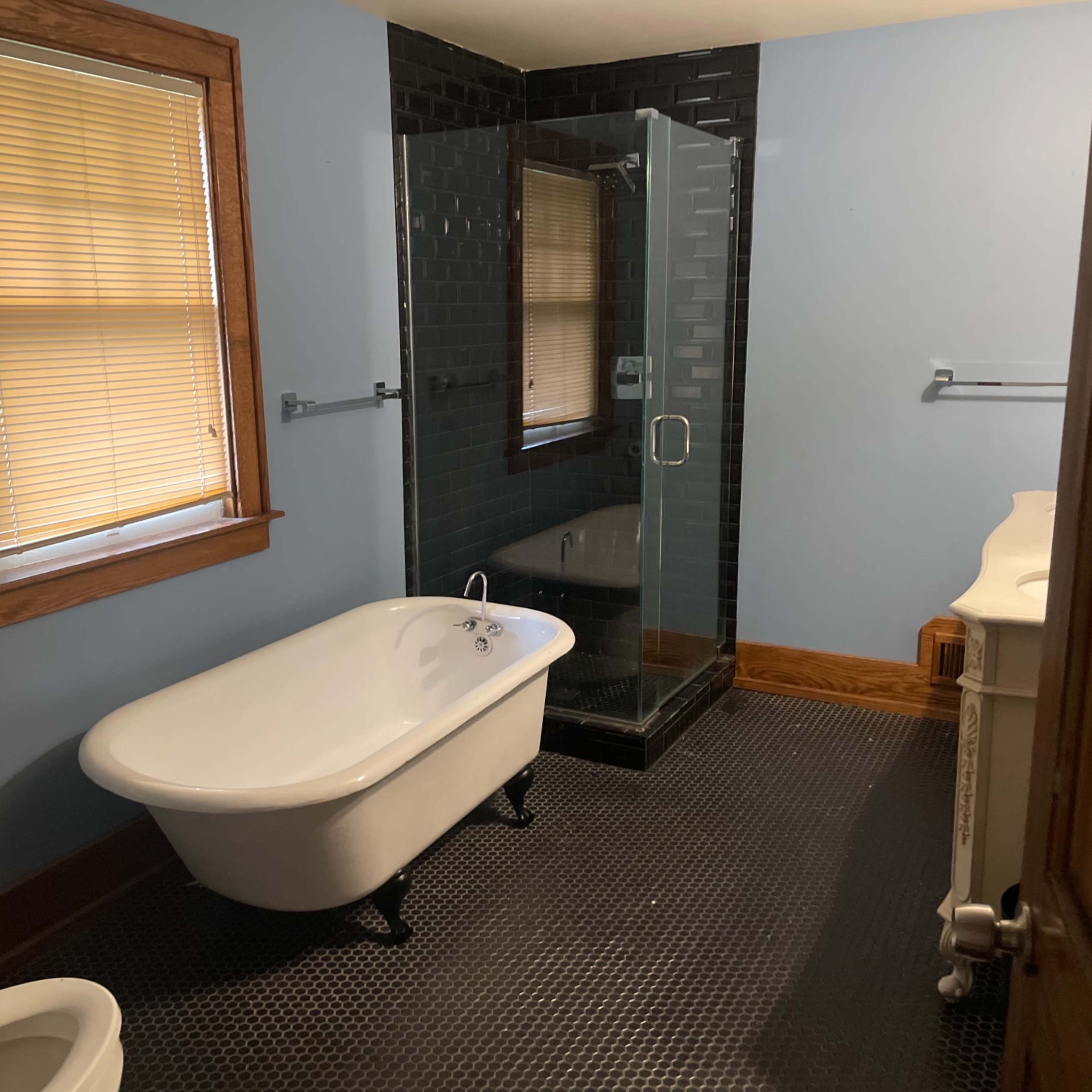 The bathroom features a freestanding bathtub, a glass shower enclosure, and a modern tile floor.