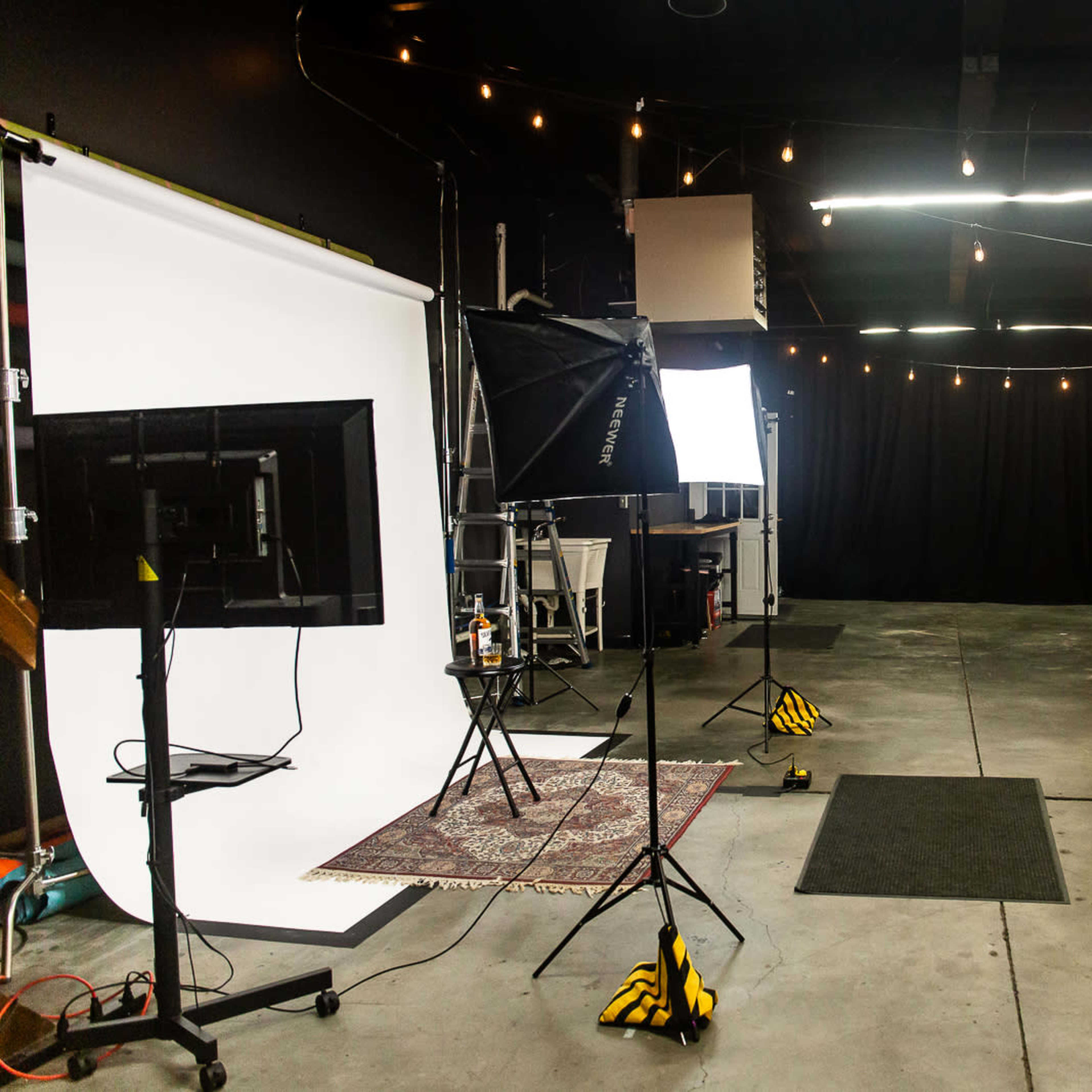 A photography studio setup with a backdrop, lighting equipment, and a large empty floor space.