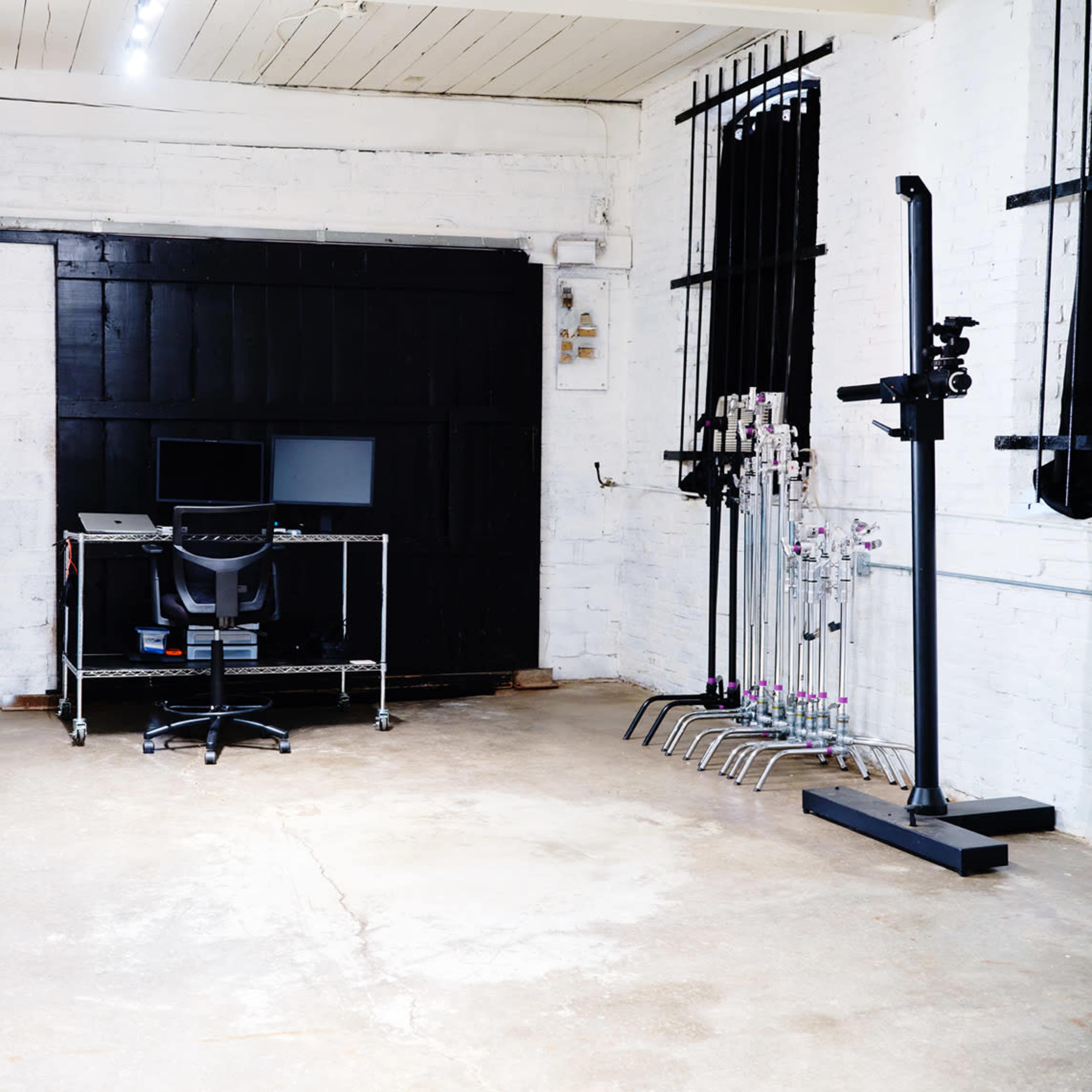 A spacious, empty room featuring a desk with a computer and a chair, along with various equipment on the walls and floor.