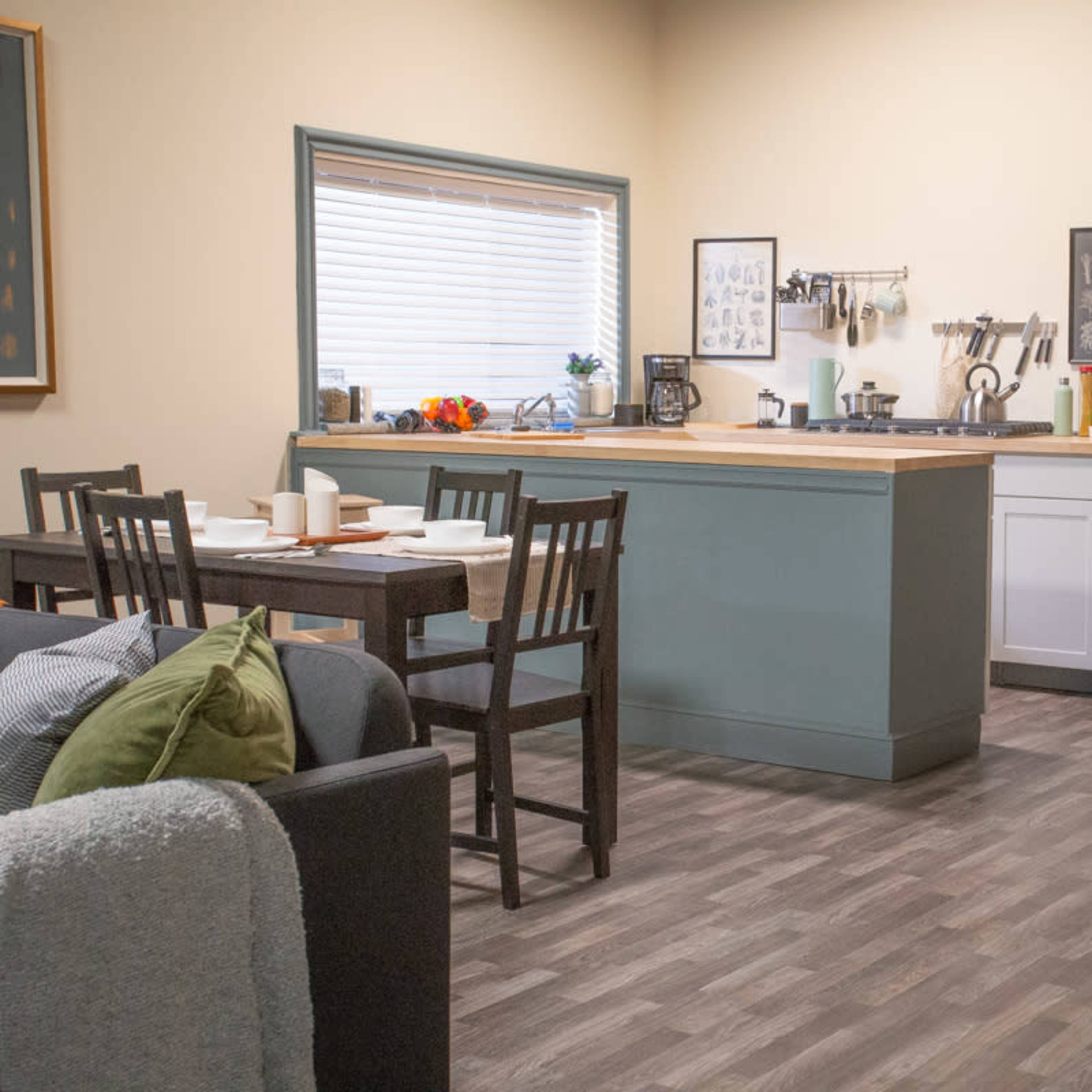 A modern kitchen and dining area featuring a table set for a meal, a stainless steel fridge, and a living room space with a sofa.