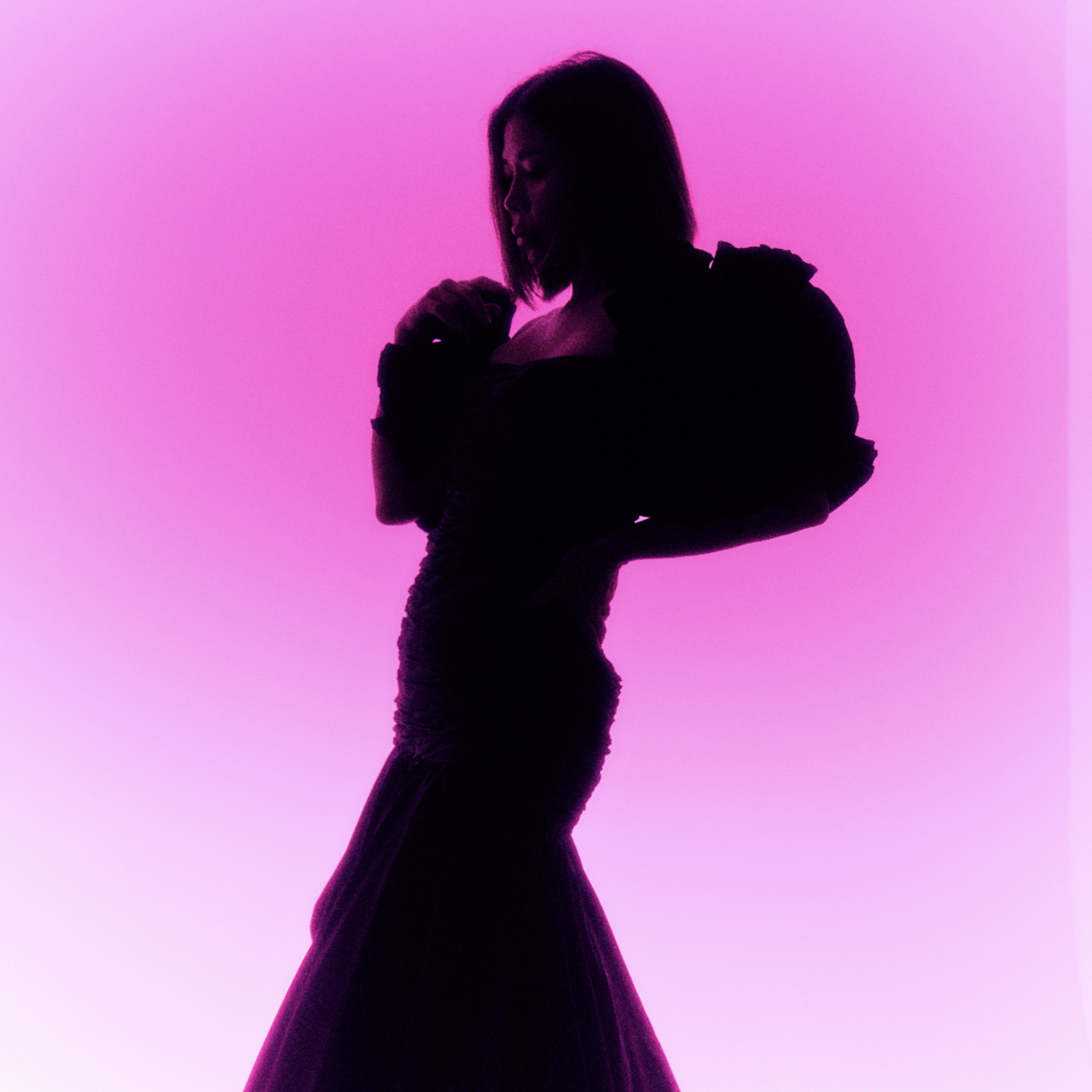 A silhouette of a woman in an elegant dress is set against a vibrant pink background.