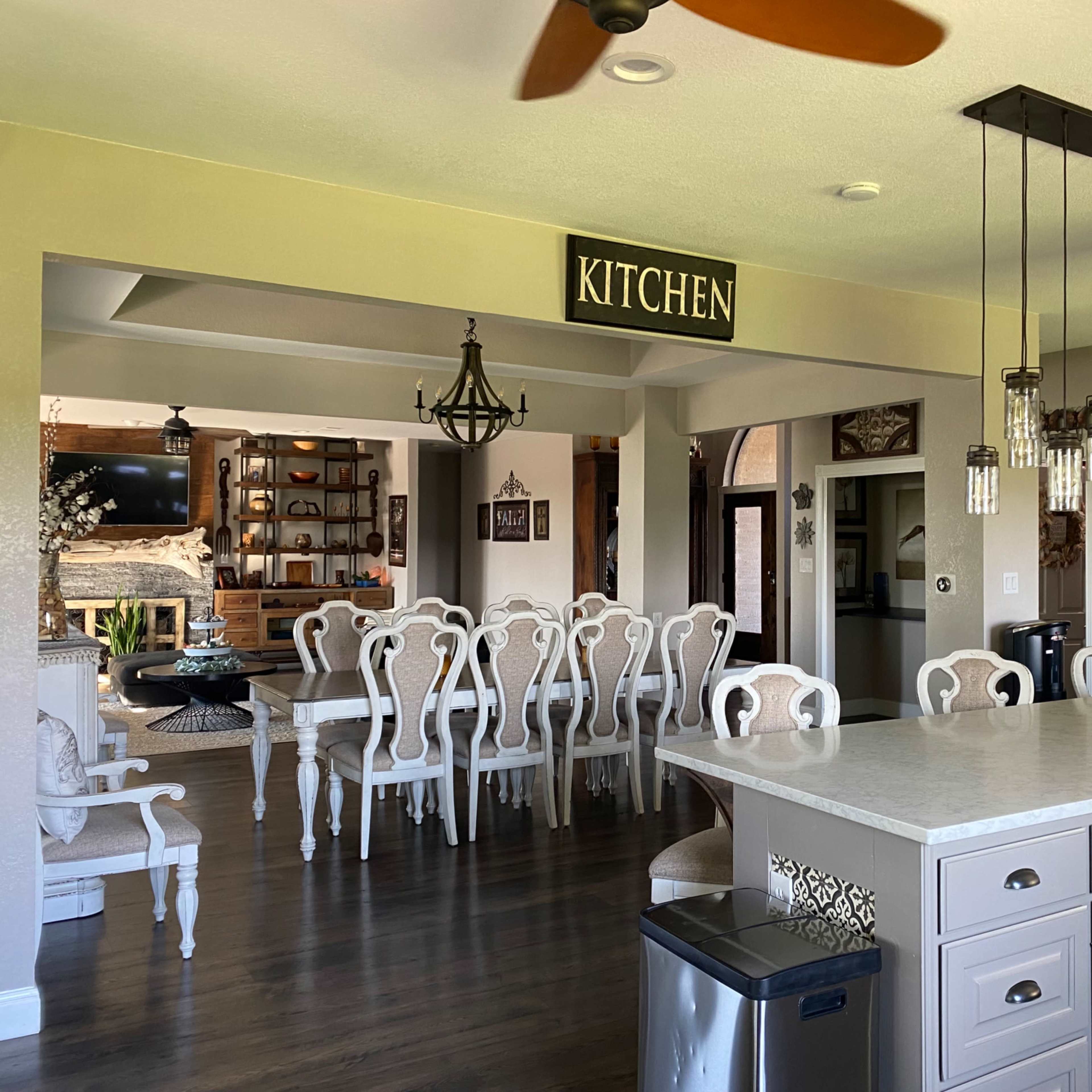 A spacious kitchen and dining area with a large island, elegant dining table, and a sign labeled "KITCHEN" above the entryway.