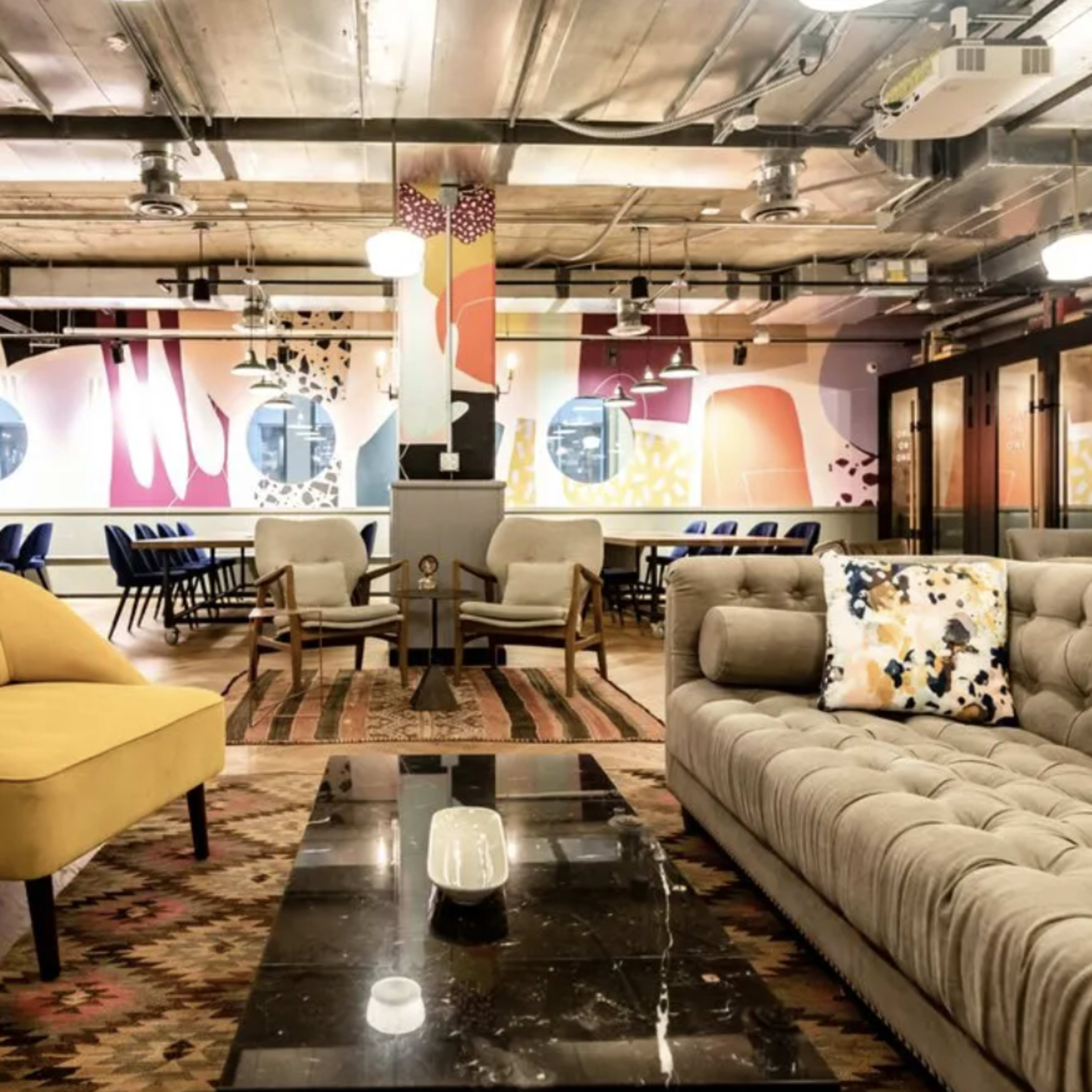 A modern co-working space featuring a mix of colorful wall art, stylish furniture, and a spacious seating area.