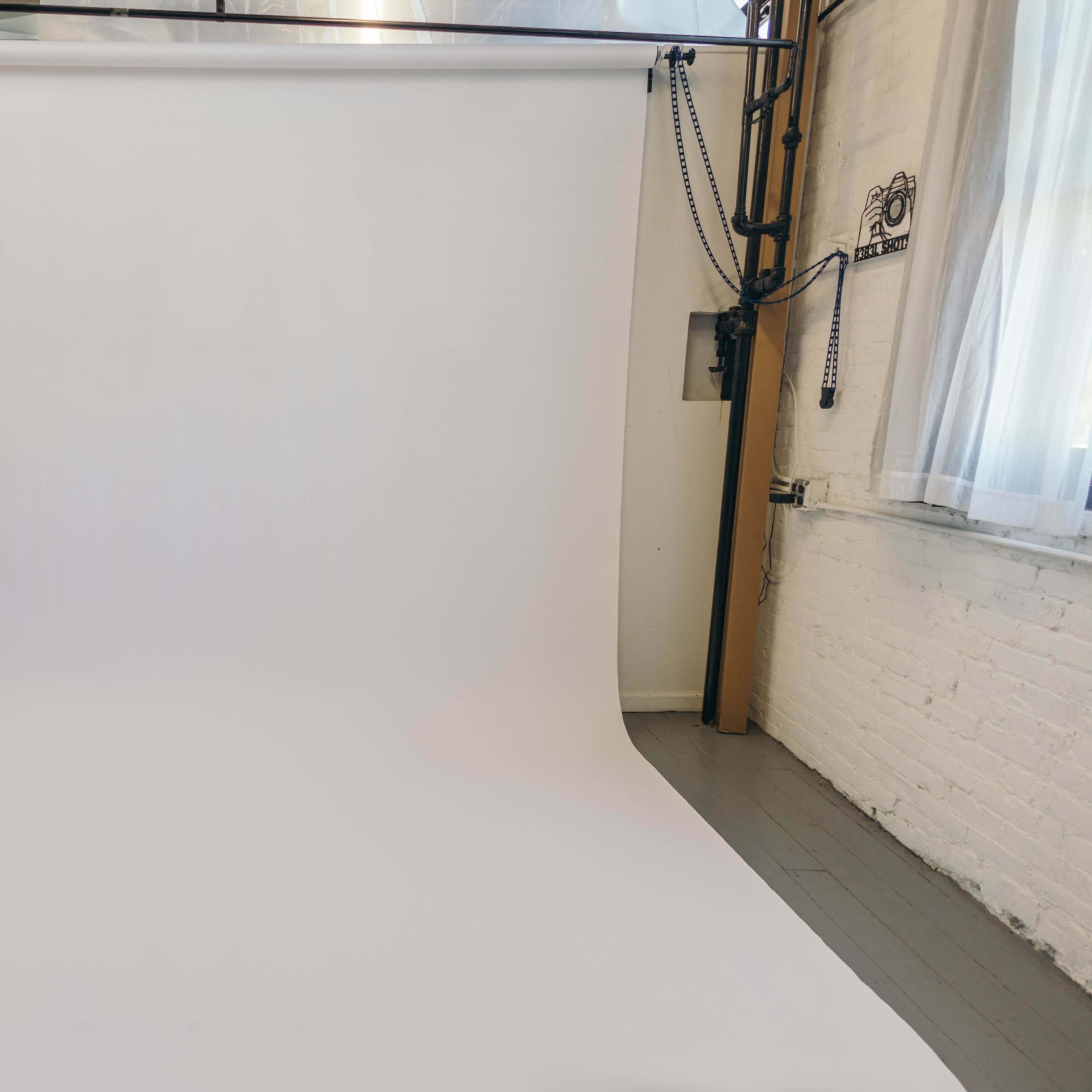 A white photo backdrop set up in a studio with minimalist surroundings.