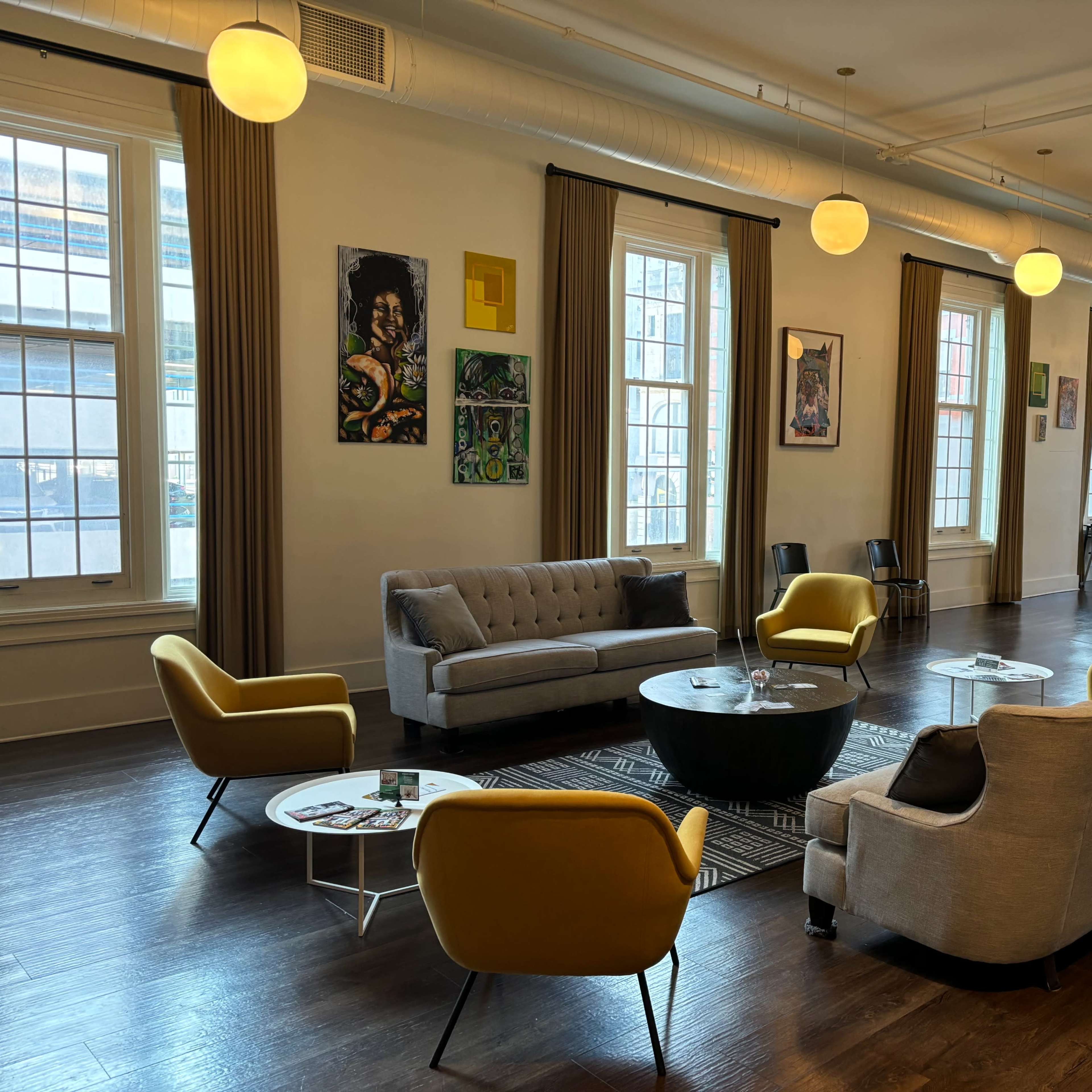 A spacious lounge area furnished with gray and yellow seating, a black coffee table, and various framed artworks on the walls.