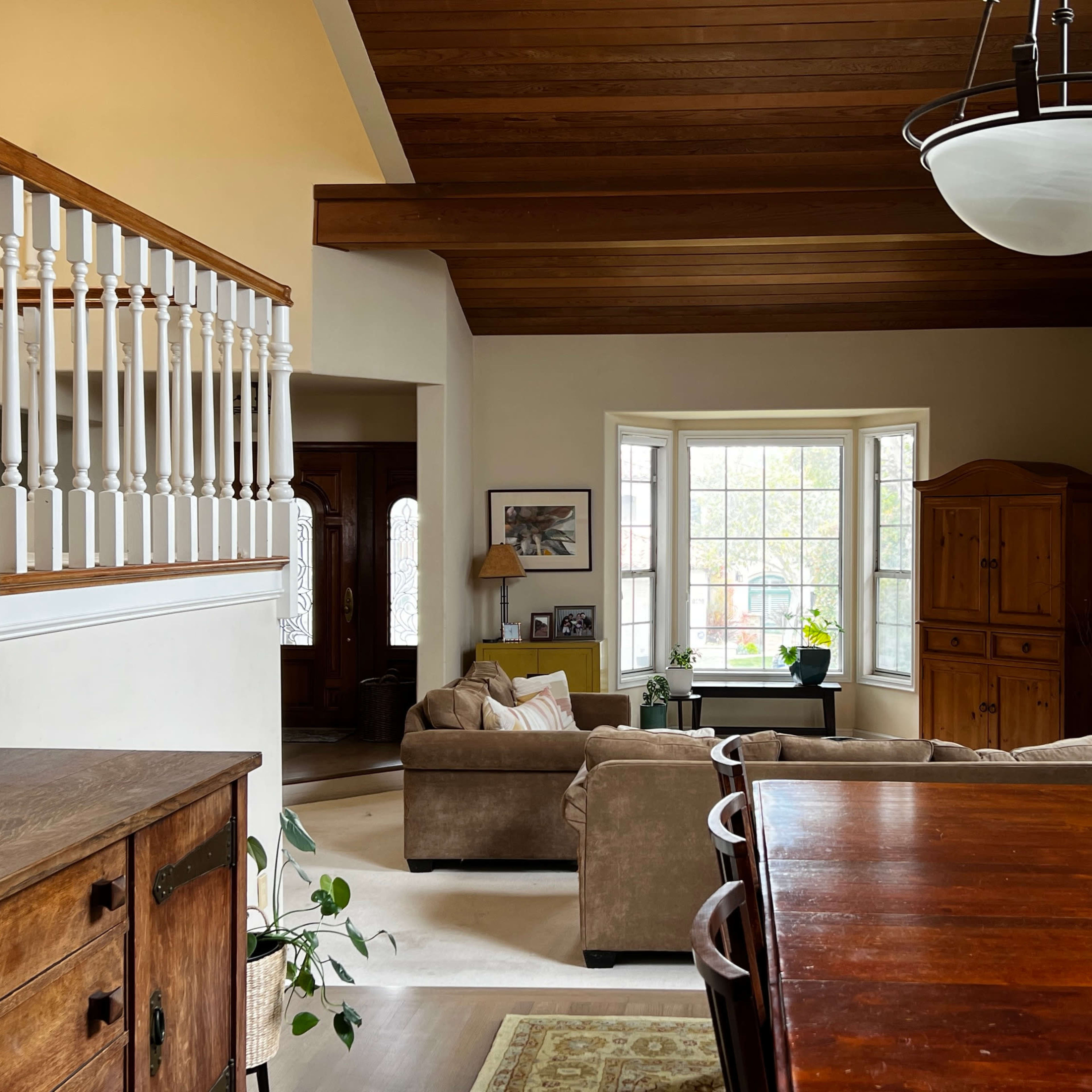 A spacious living area with a dining table, a couch, and large windows allowing natural light to enter.
