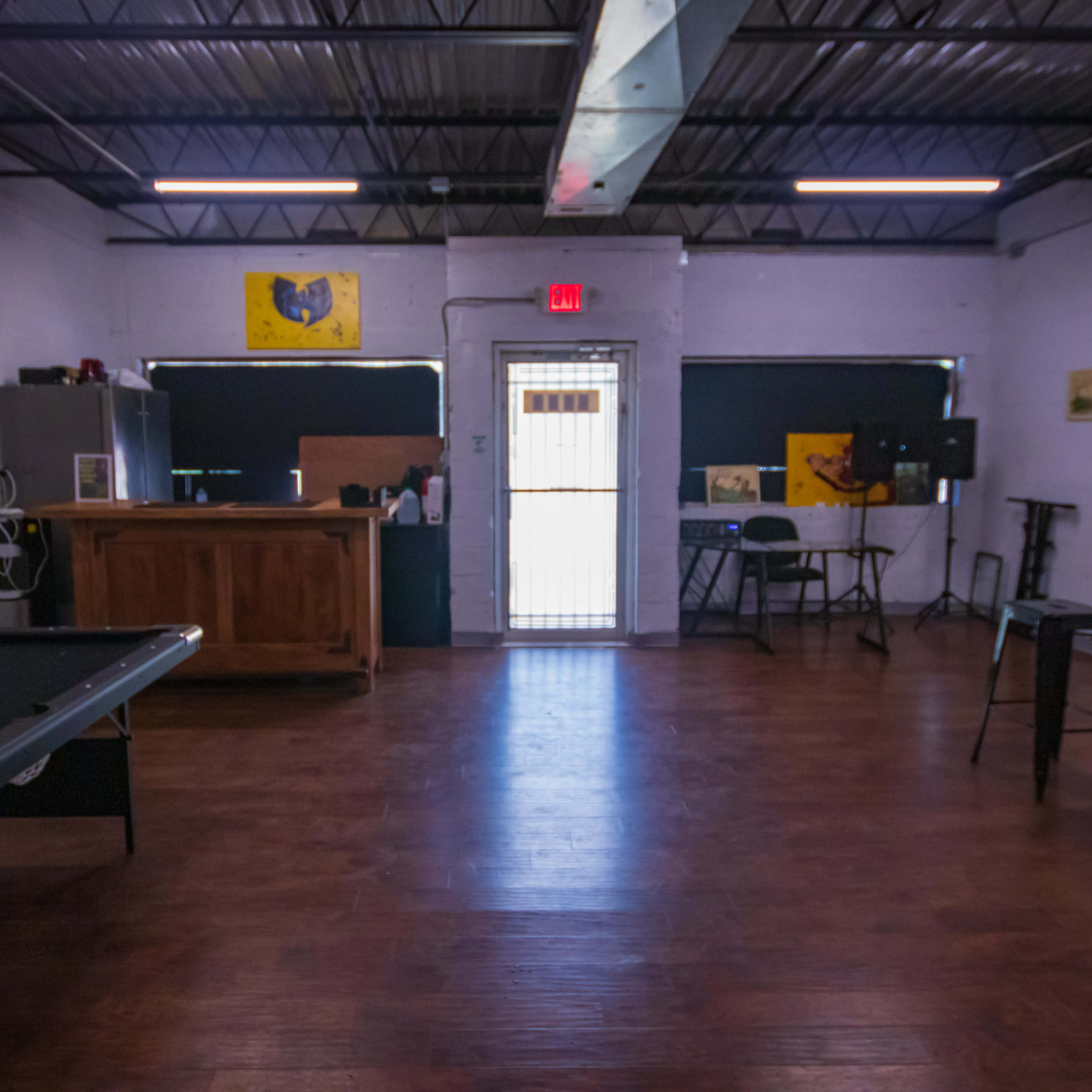 An interior room featuring a pool table, a wooden bar, and several pieces of artwork on the walls.