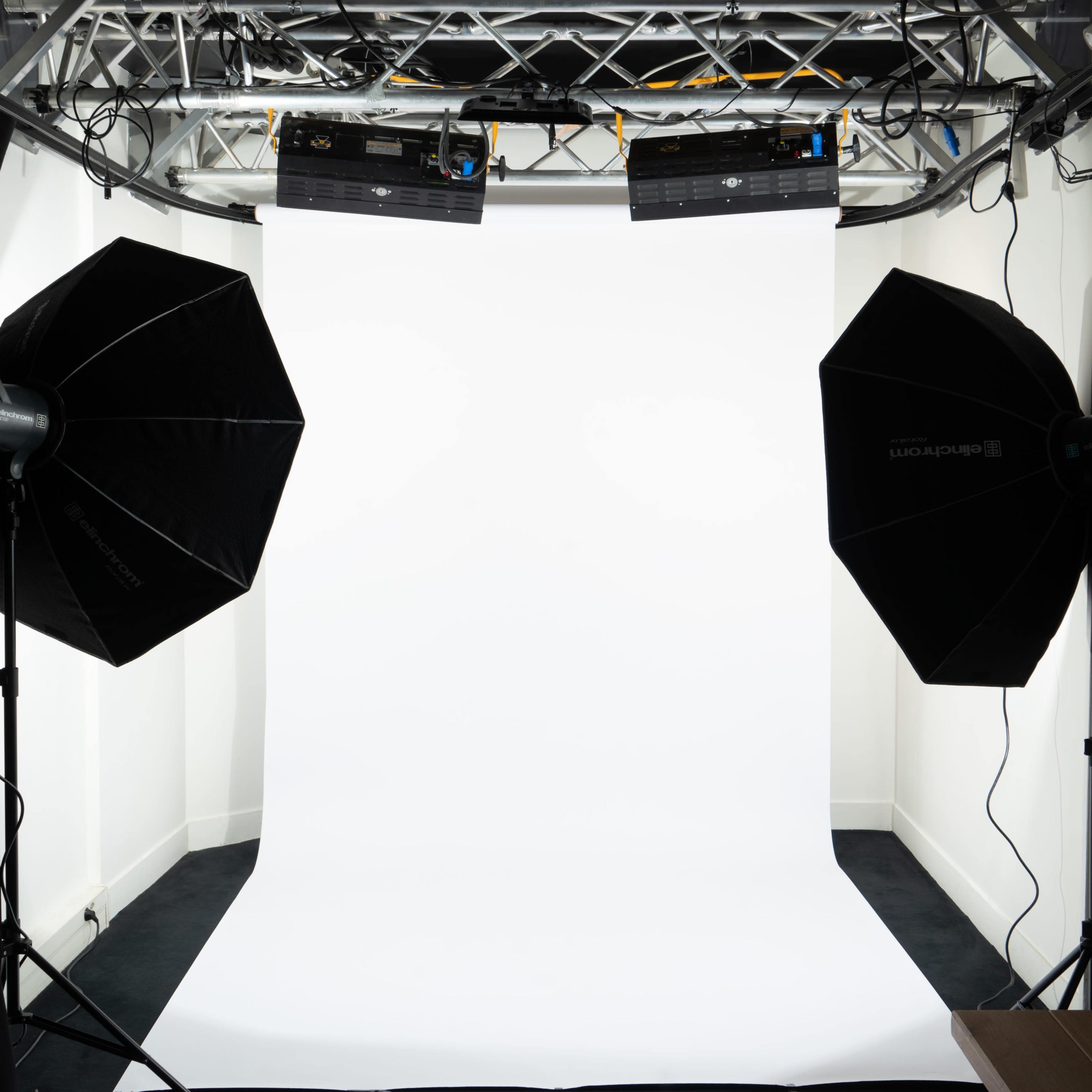 A photography studio setup featuring two light sources directed at a white backdrop.
