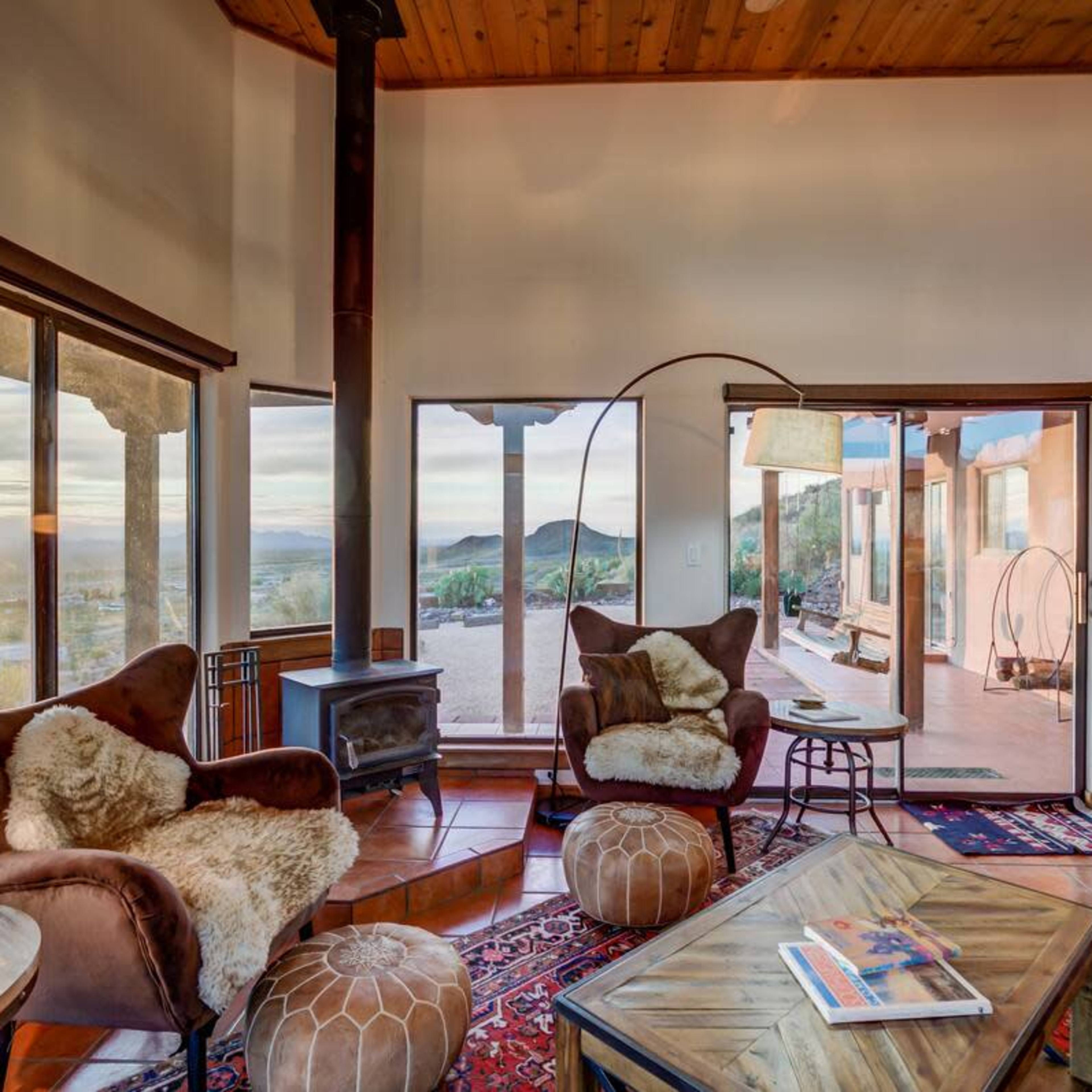 A cozy living room featuring two armchairs, a wooden coffee table, and large windows that provide a view of the outdoors.