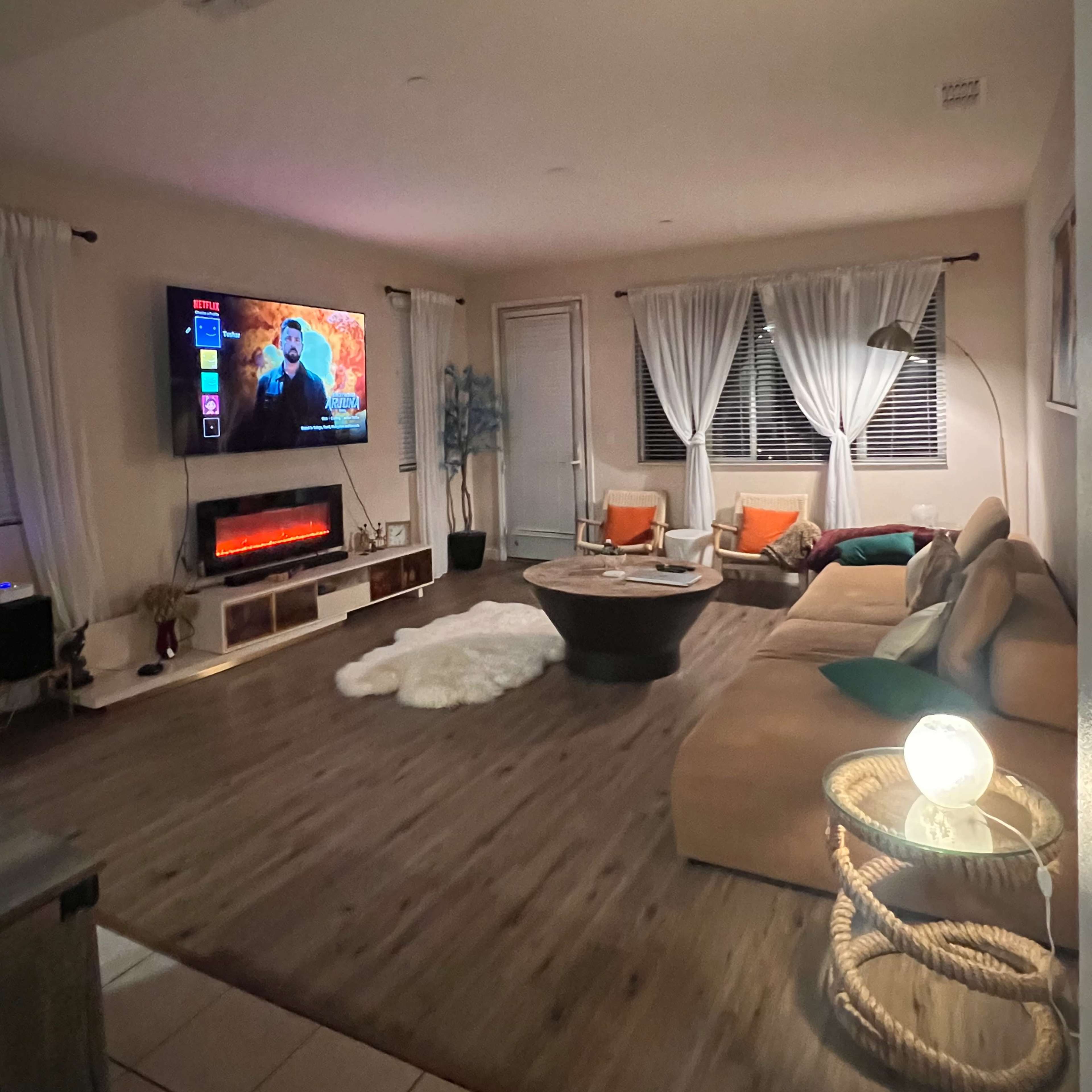 The living room features a sectional sofa, a coffee table, an electric fireplace, and a wall-mounted television.