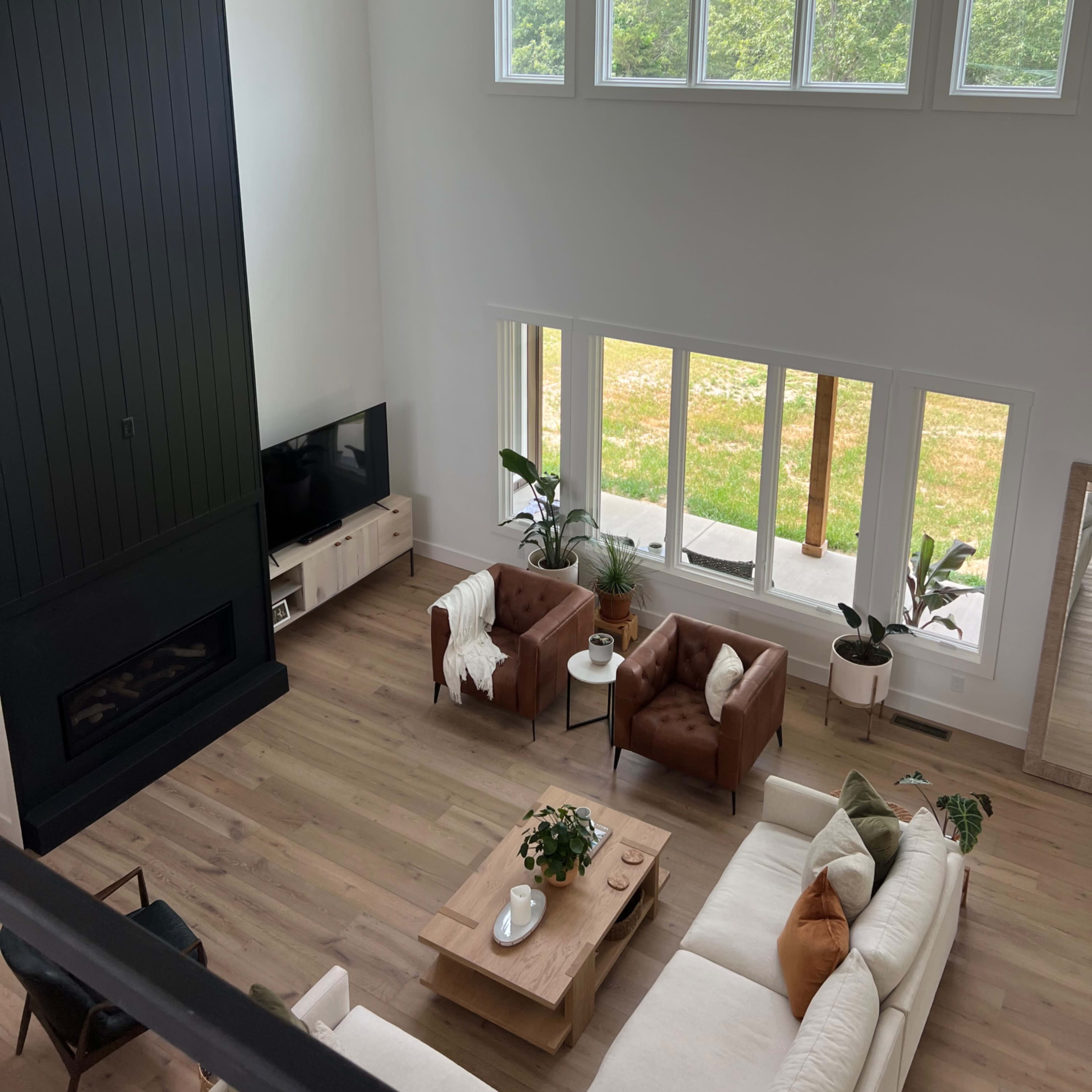 A spacious living room with a large window, modern furniture, and a fireplace, showcasing a clean and minimalist design.