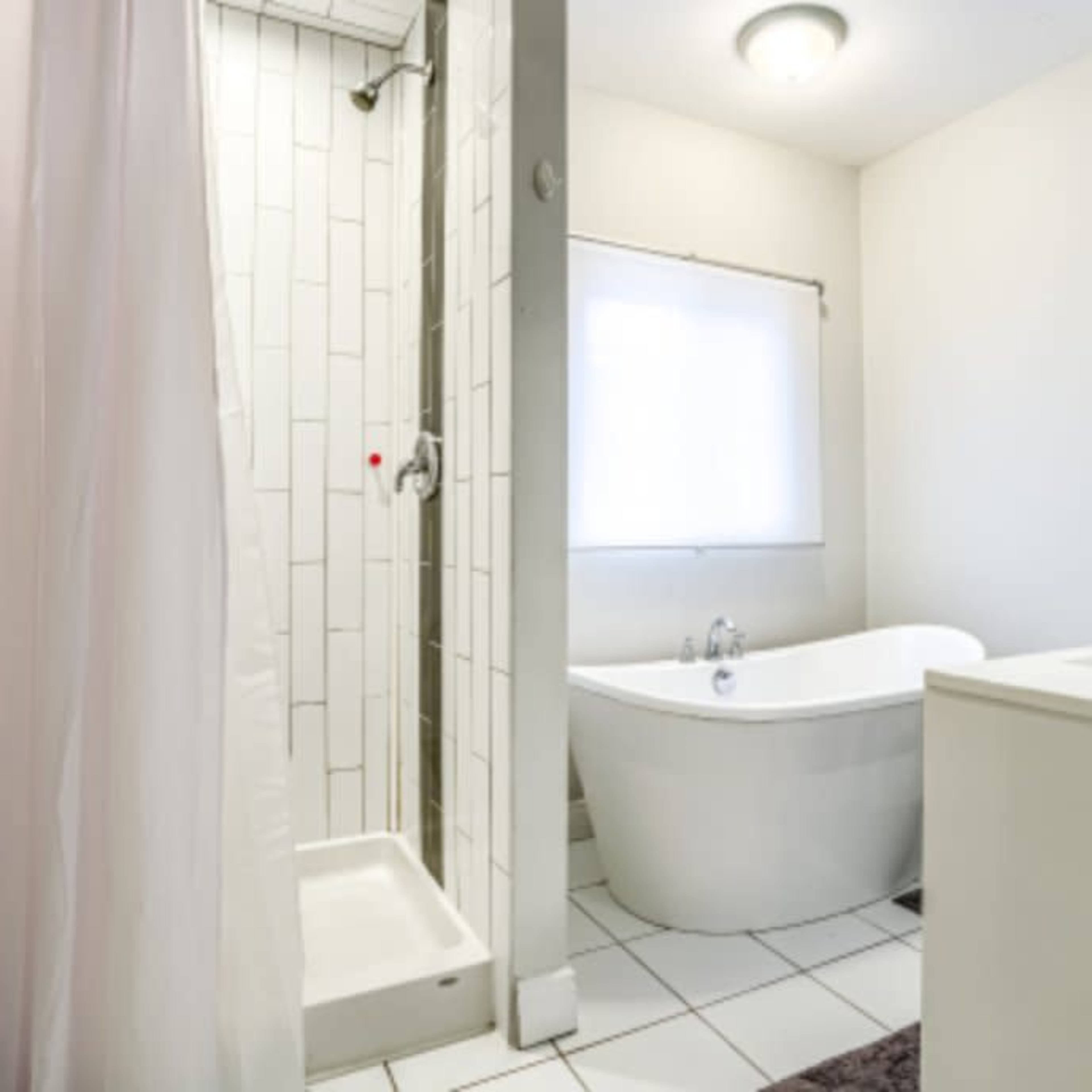 A bathroom featuring a shower with glass doors, a freestanding bathtub, and a window for natural light.