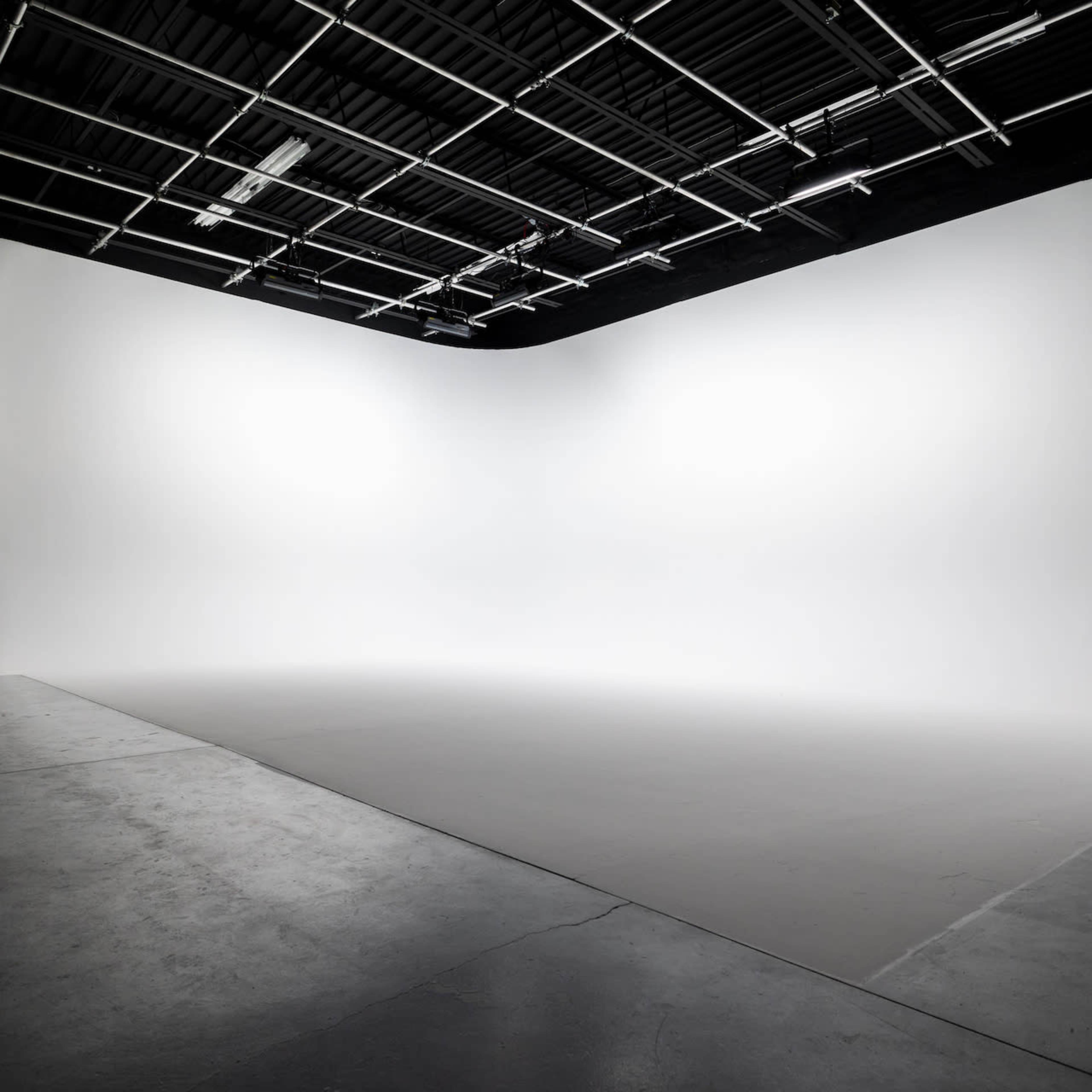 A spacious photography studio with a seamless white backdrop and a clean, empty floor.