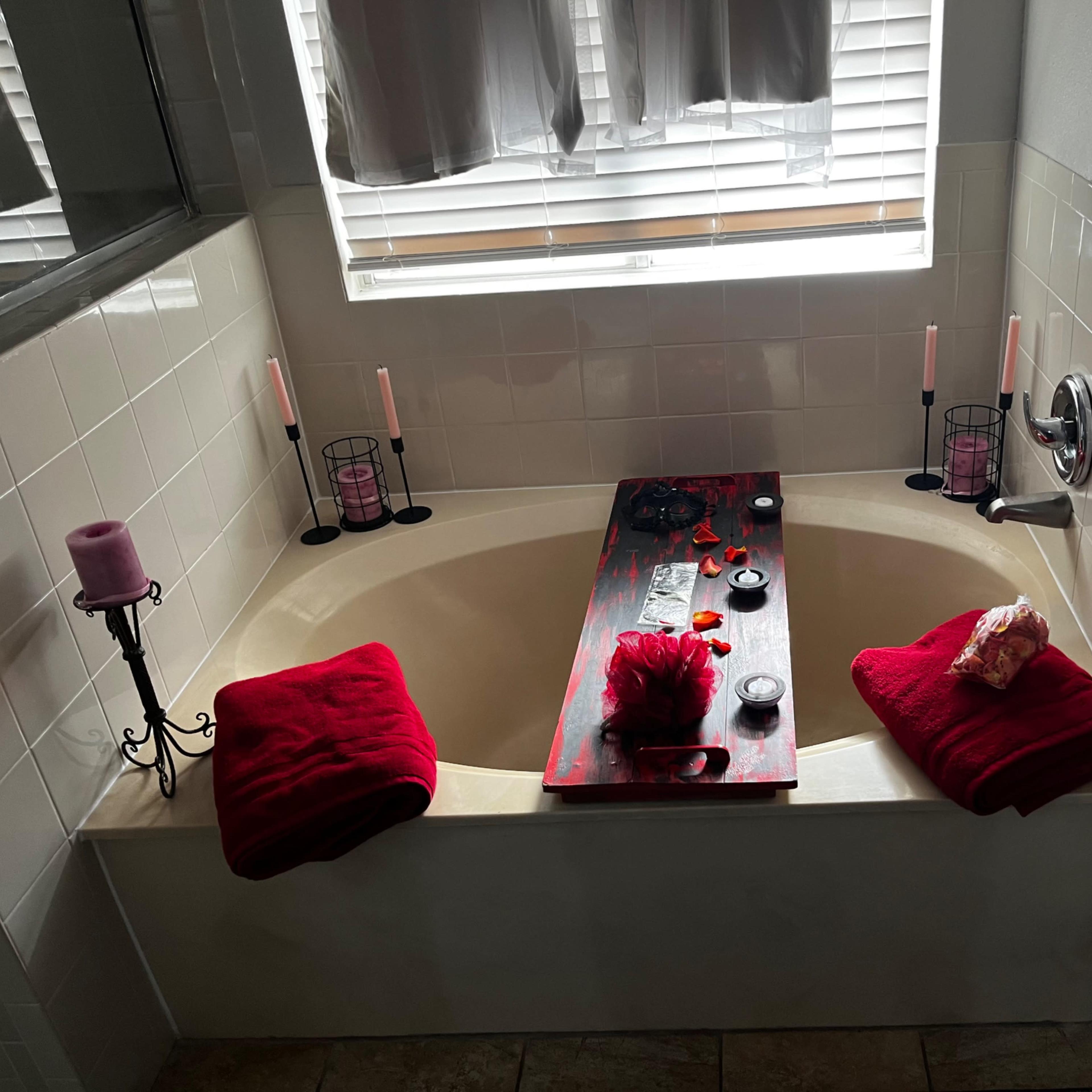 A bathroom with a bathtub surrounded by candles, towels, and decorative items.