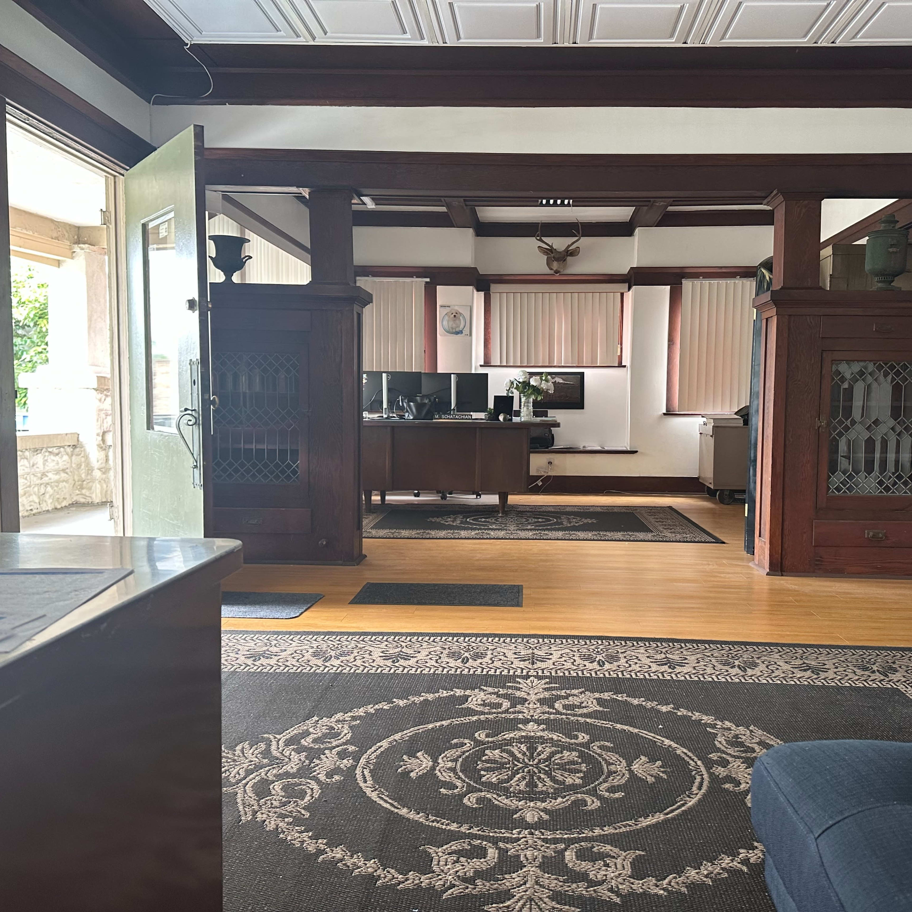 An organized office space with wooden paneling, a large desk in the background, and a couch on the right side.