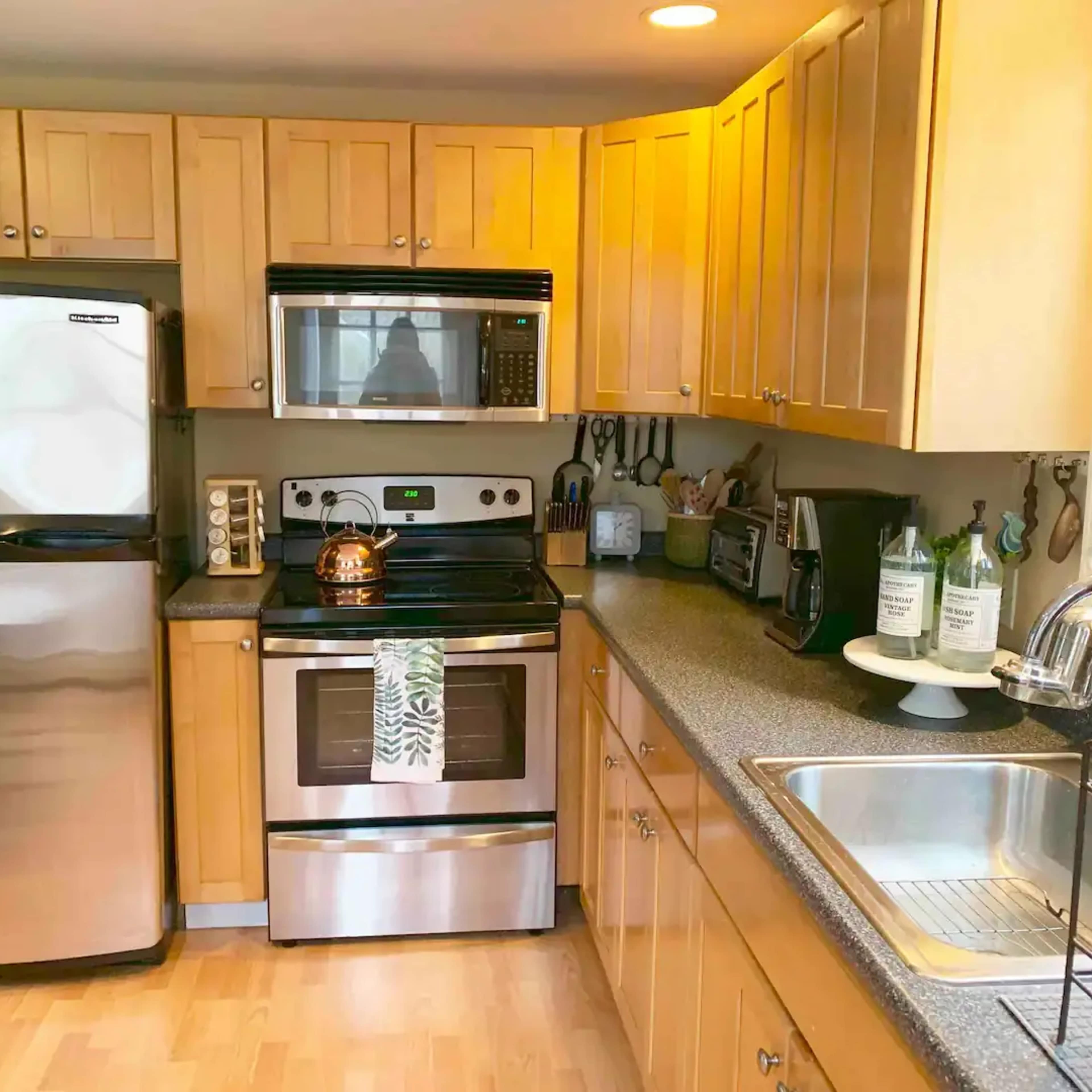A modern kitchen features stainless steel appliances, wooden cabinetry, and a countertop with a sink and decorative items.