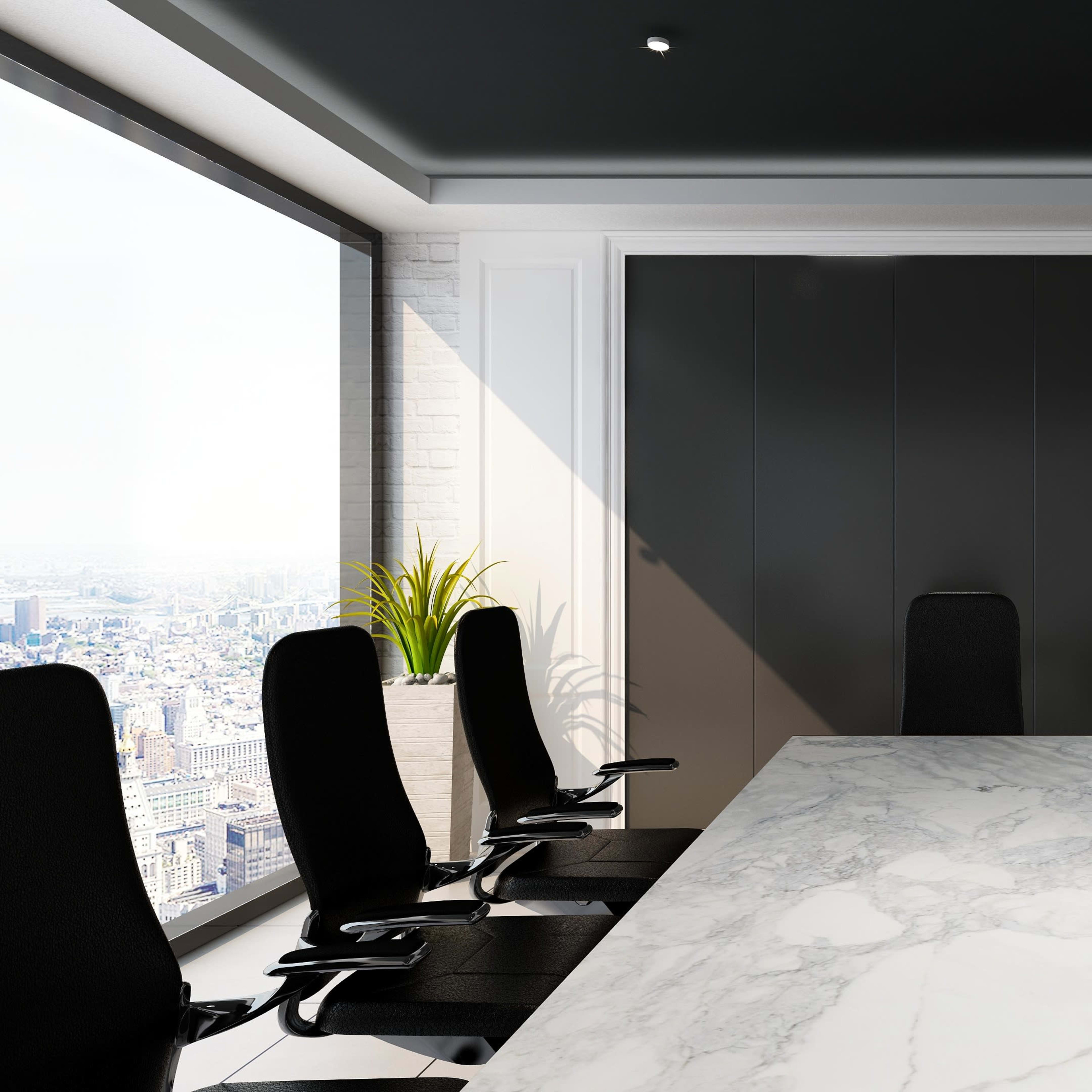 A modern conference room features a long marble table surrounded by black ergonomic chairs and large windows overlooking a cityscape.