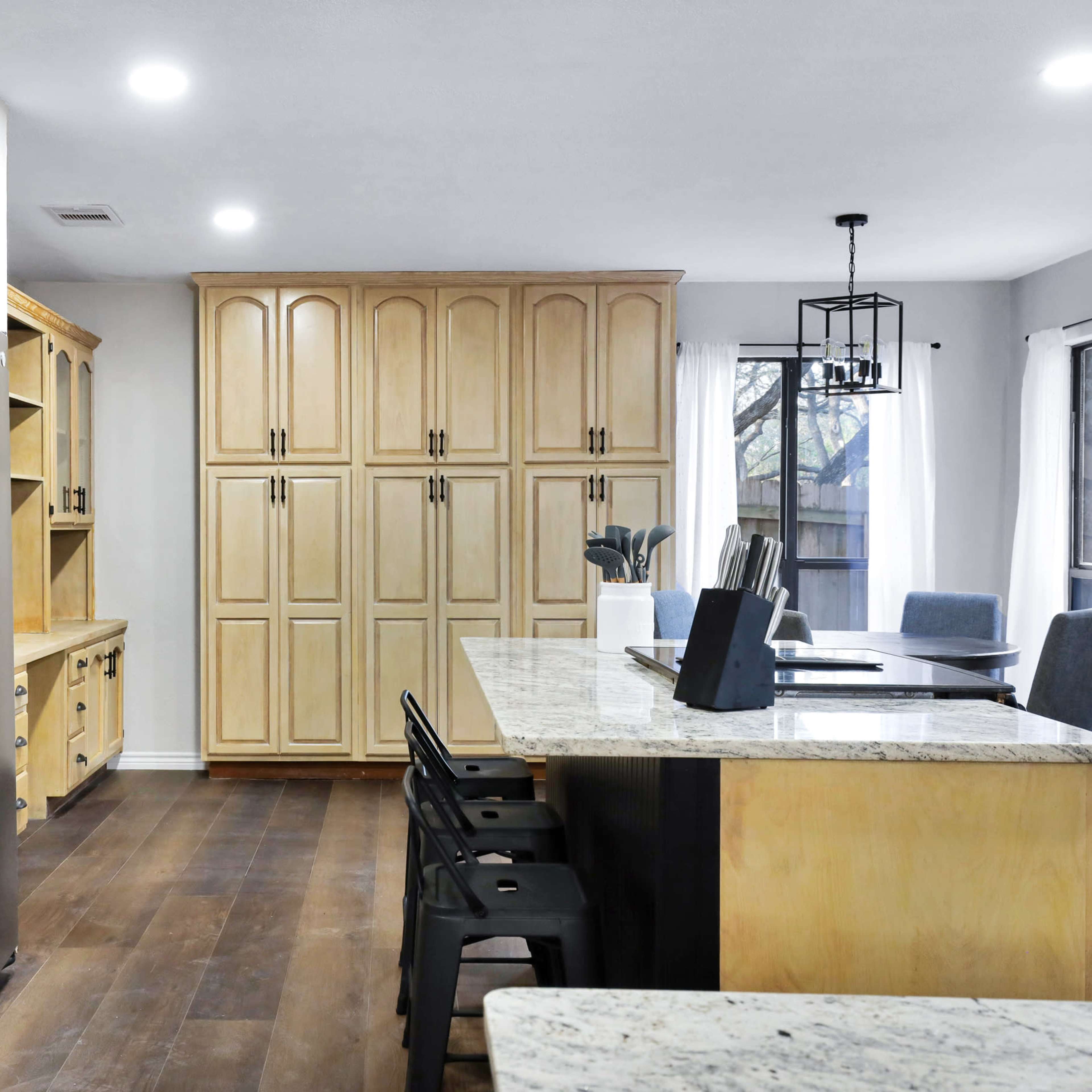 A modern kitchen featuring wooden cabinetry, a large island with seating, granite countertops, and stainless steel appliances.