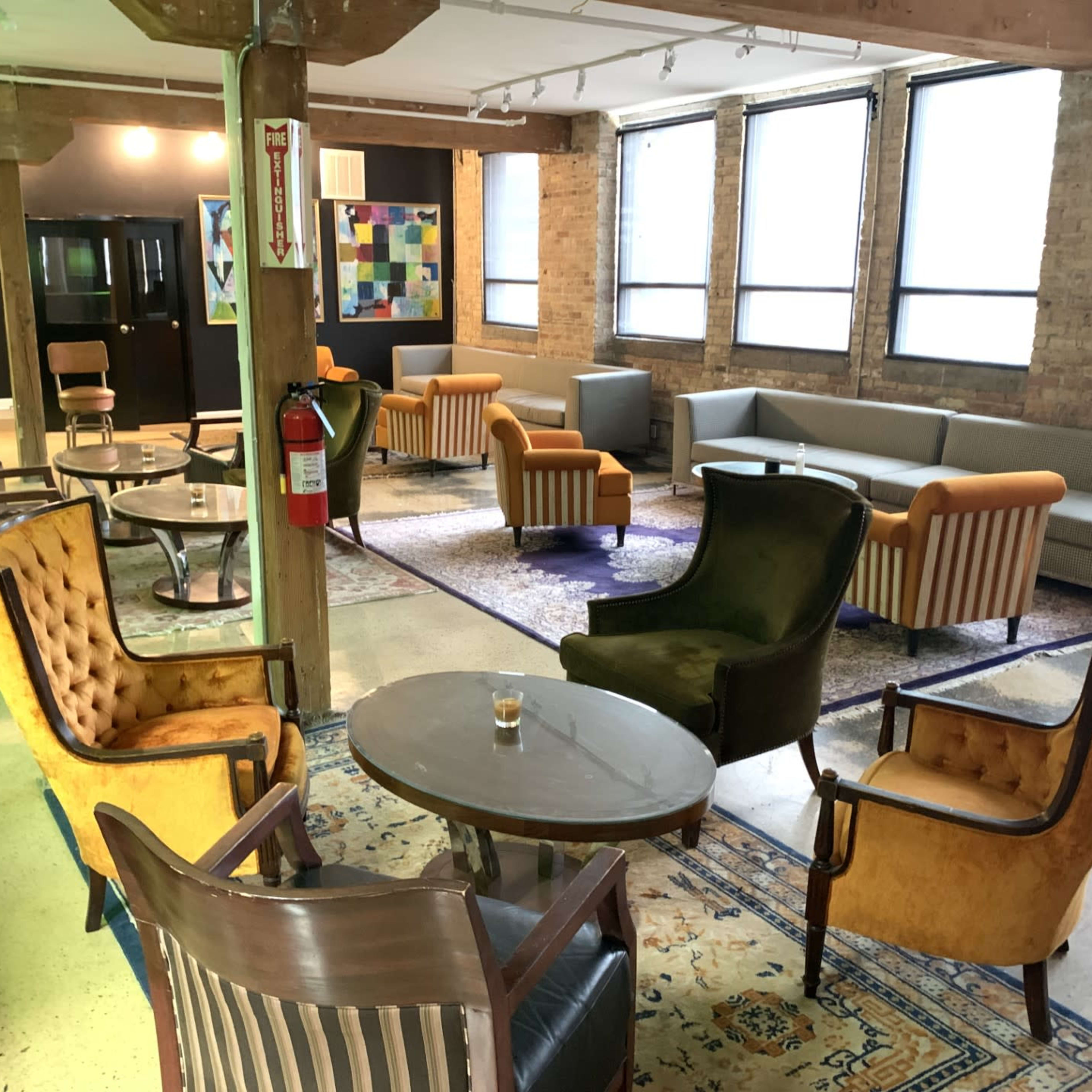 A spacious lounge area furnished with various seating arrangements, including armchairs and sofas, along with a central coffee table and decor on the walls.