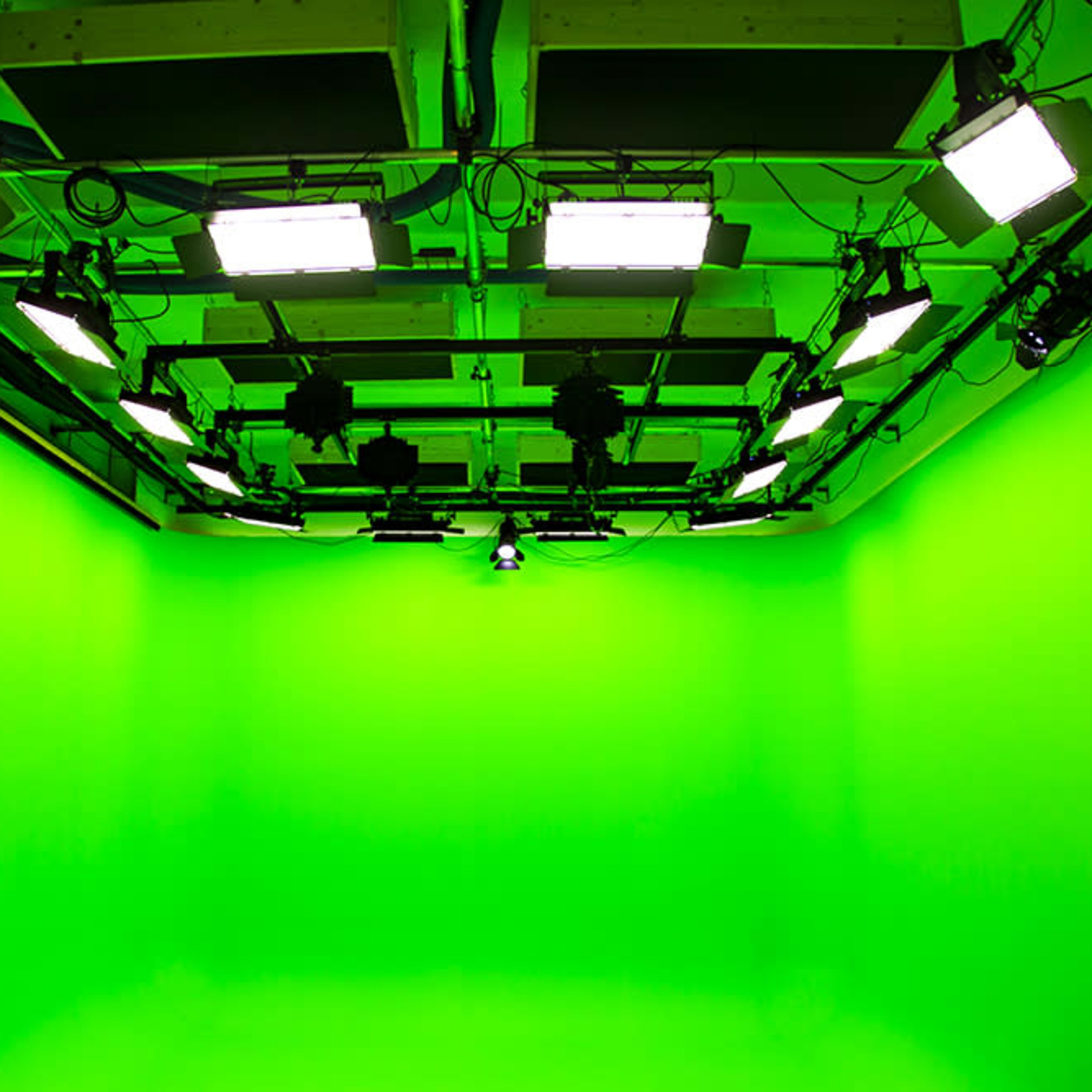 A green screen studio with bright lights mounted on the ceiling.