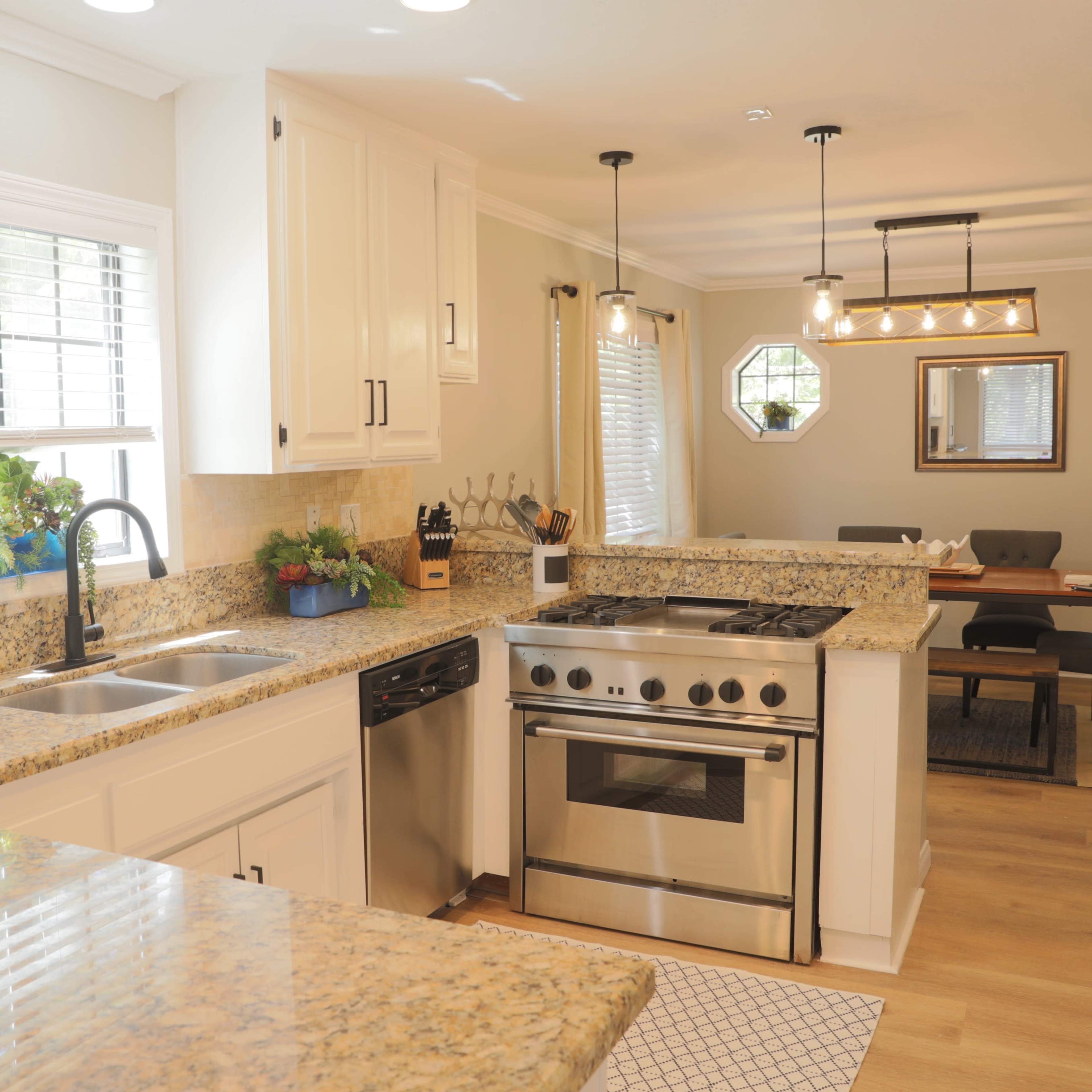 A modern kitchen with granite countertops, stainless steel appliances, and a dining area visible in the background.