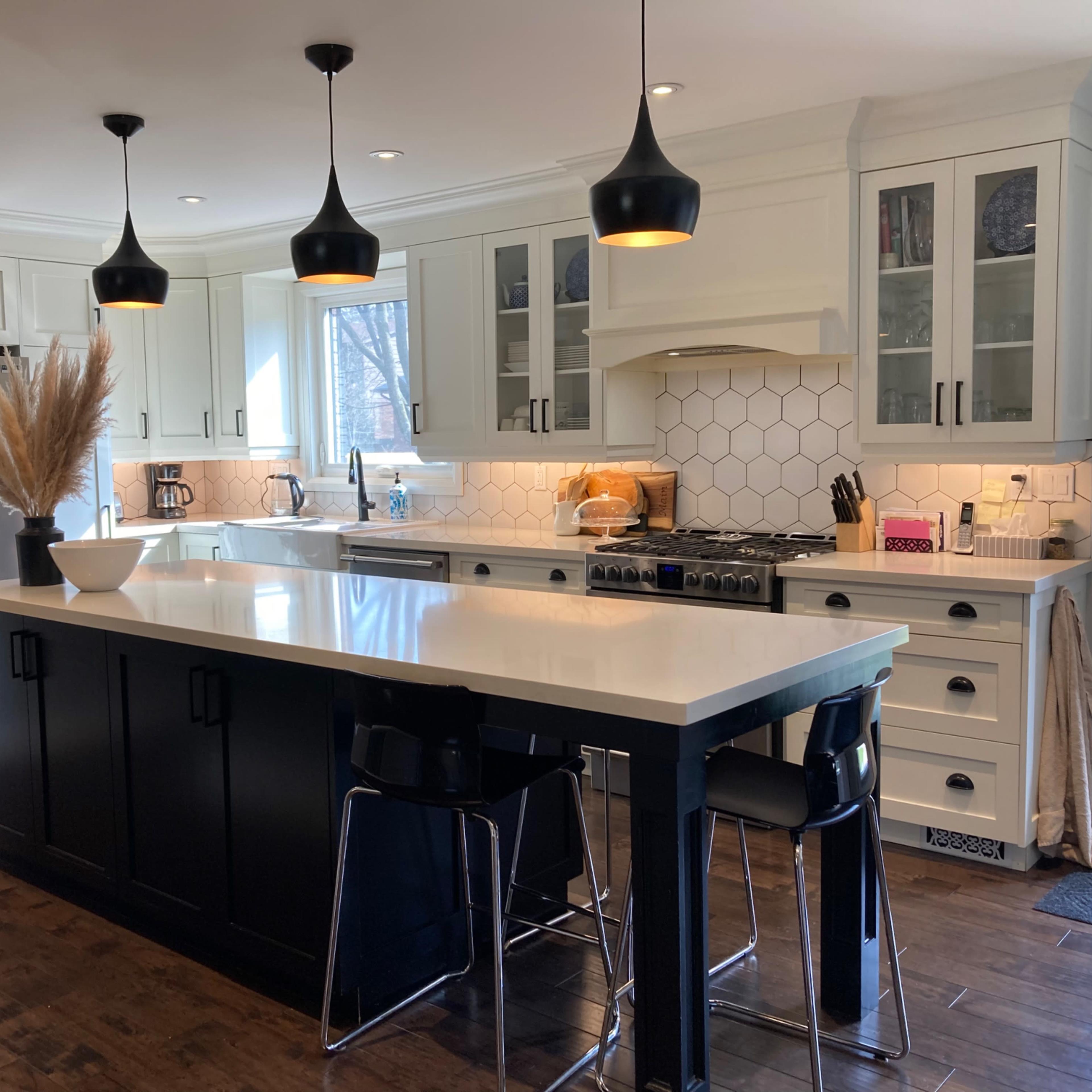 The kitchen features a large central island with a dark base, white cabinetry, modern appliances, and pendant lighting.