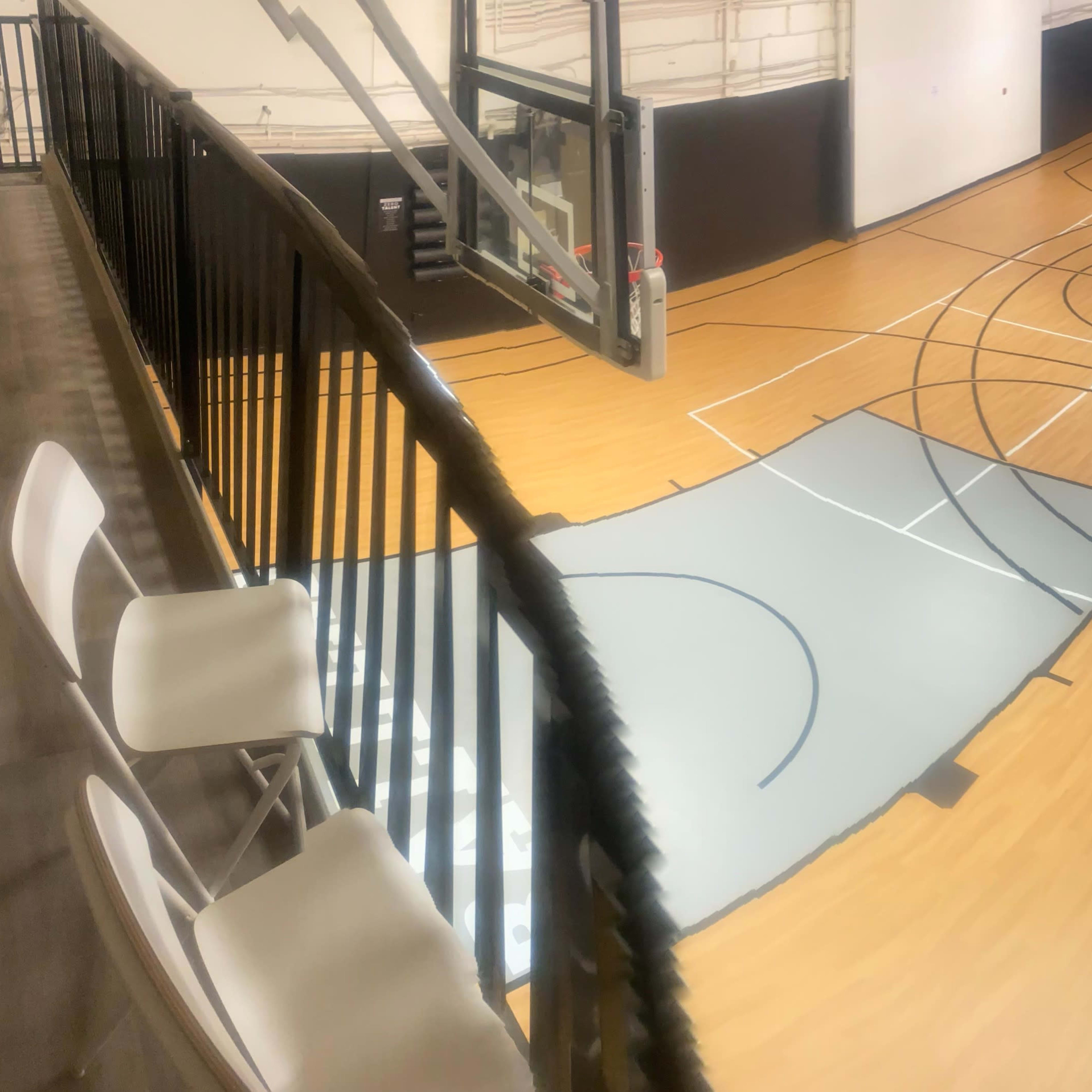 An indoor sports facility with wooden flooring featuring multiple basketball court outlines and areas marked in gray.