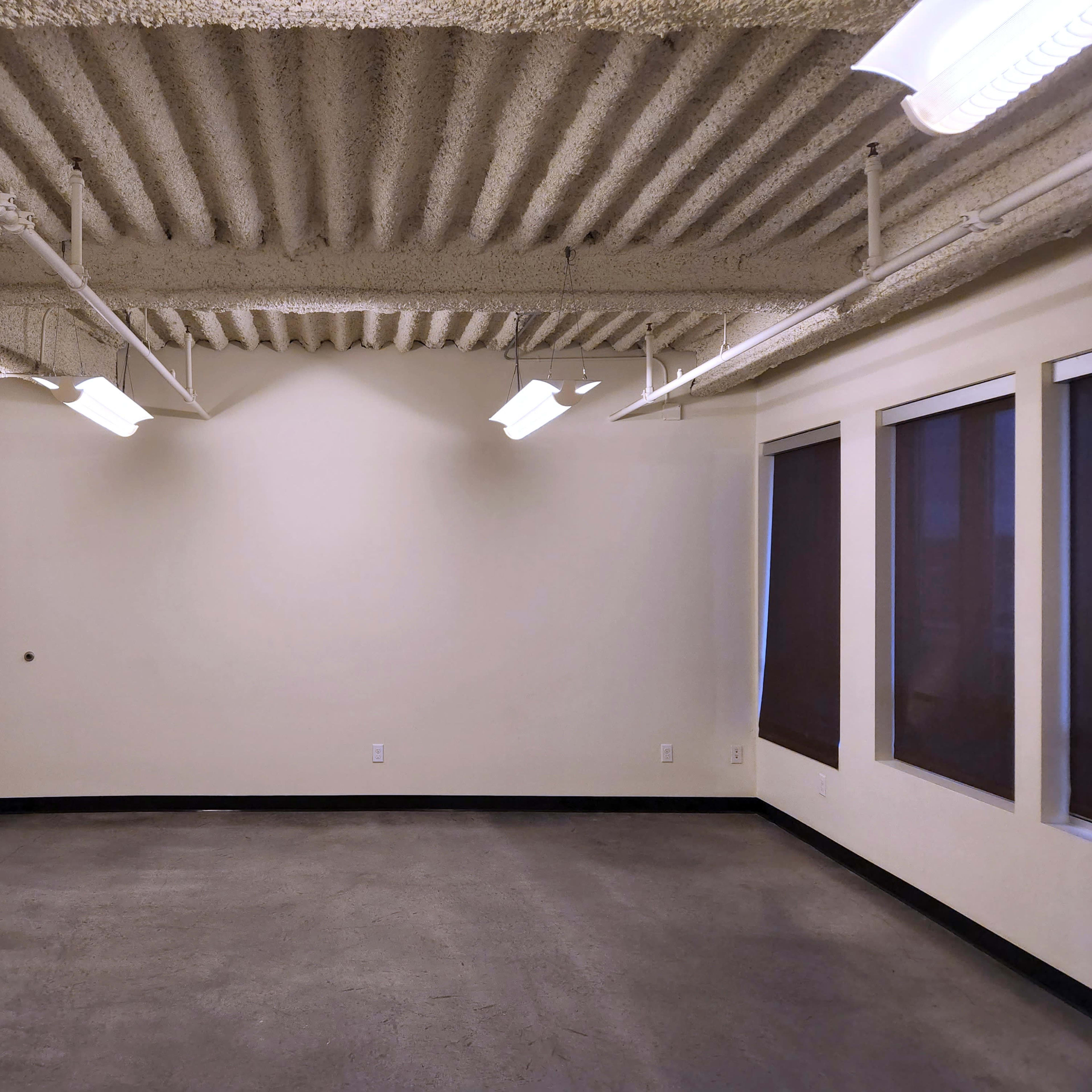 An empty room with a concrete floor, textured ceiling, and a door on one side.