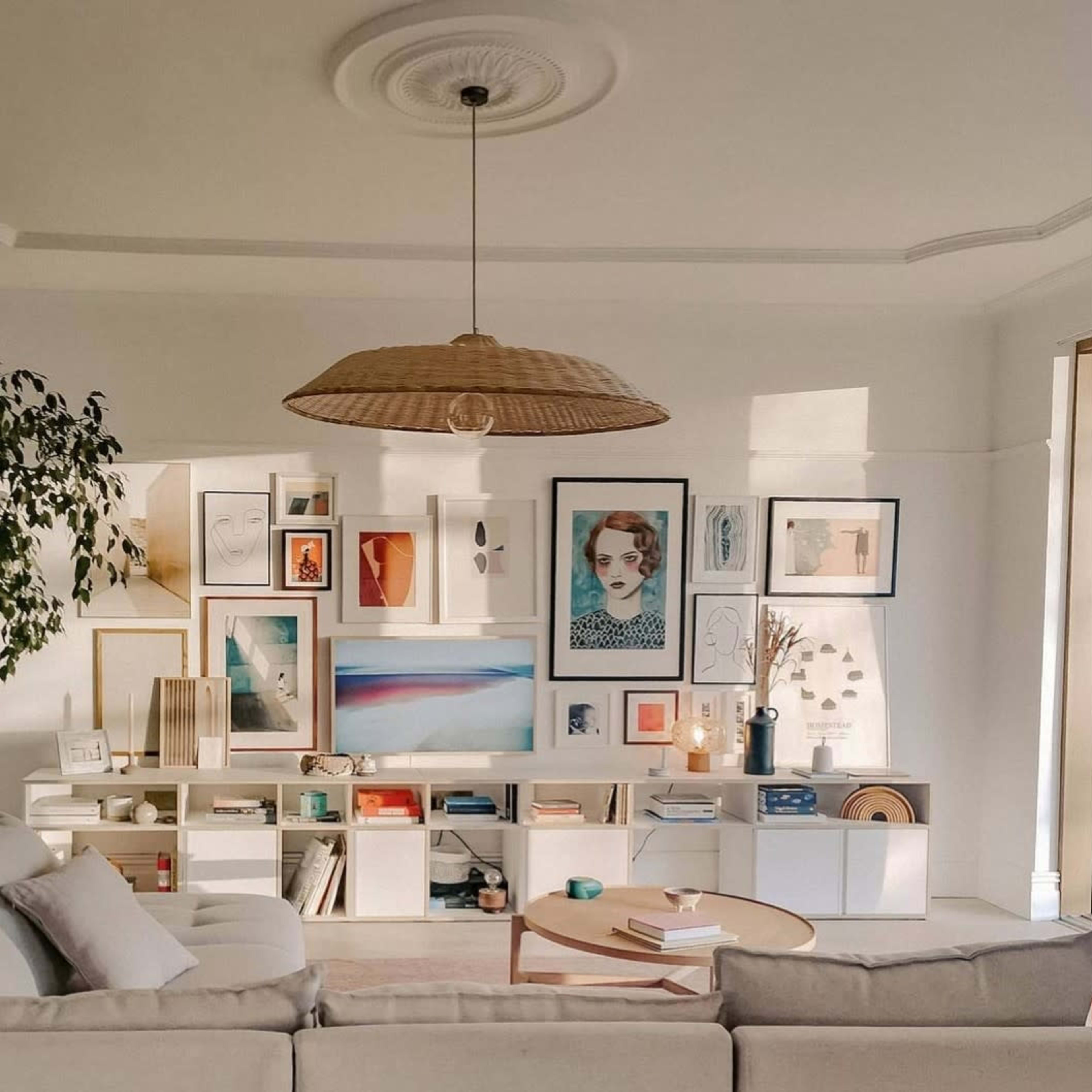 A well-organized living room featuring a large beige sofa, a wooden coffee table, and a gallery wall adorned with various framed artworks.