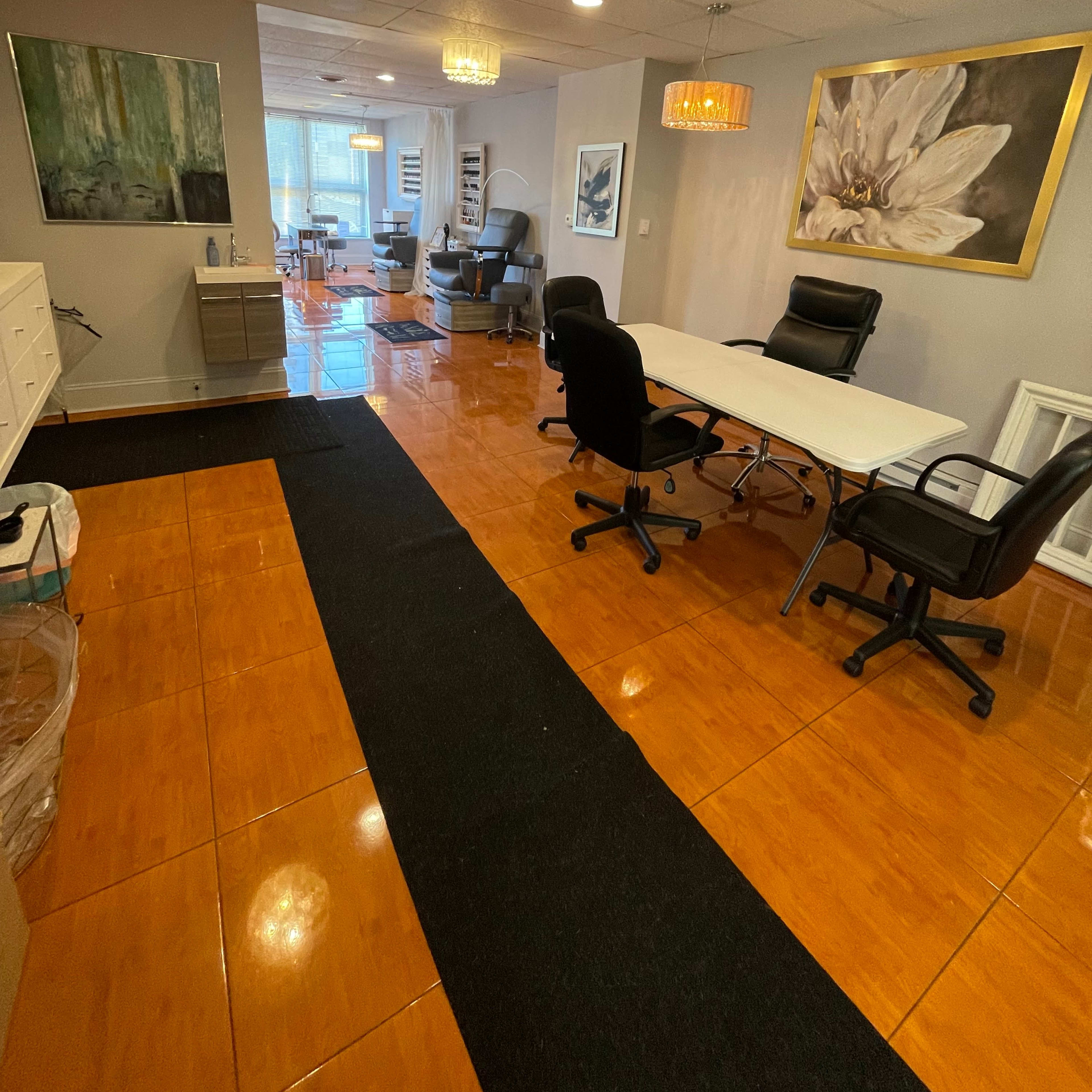 A well-lit office space featuring a reception area with a white table, chairs, and artwork on the walls.