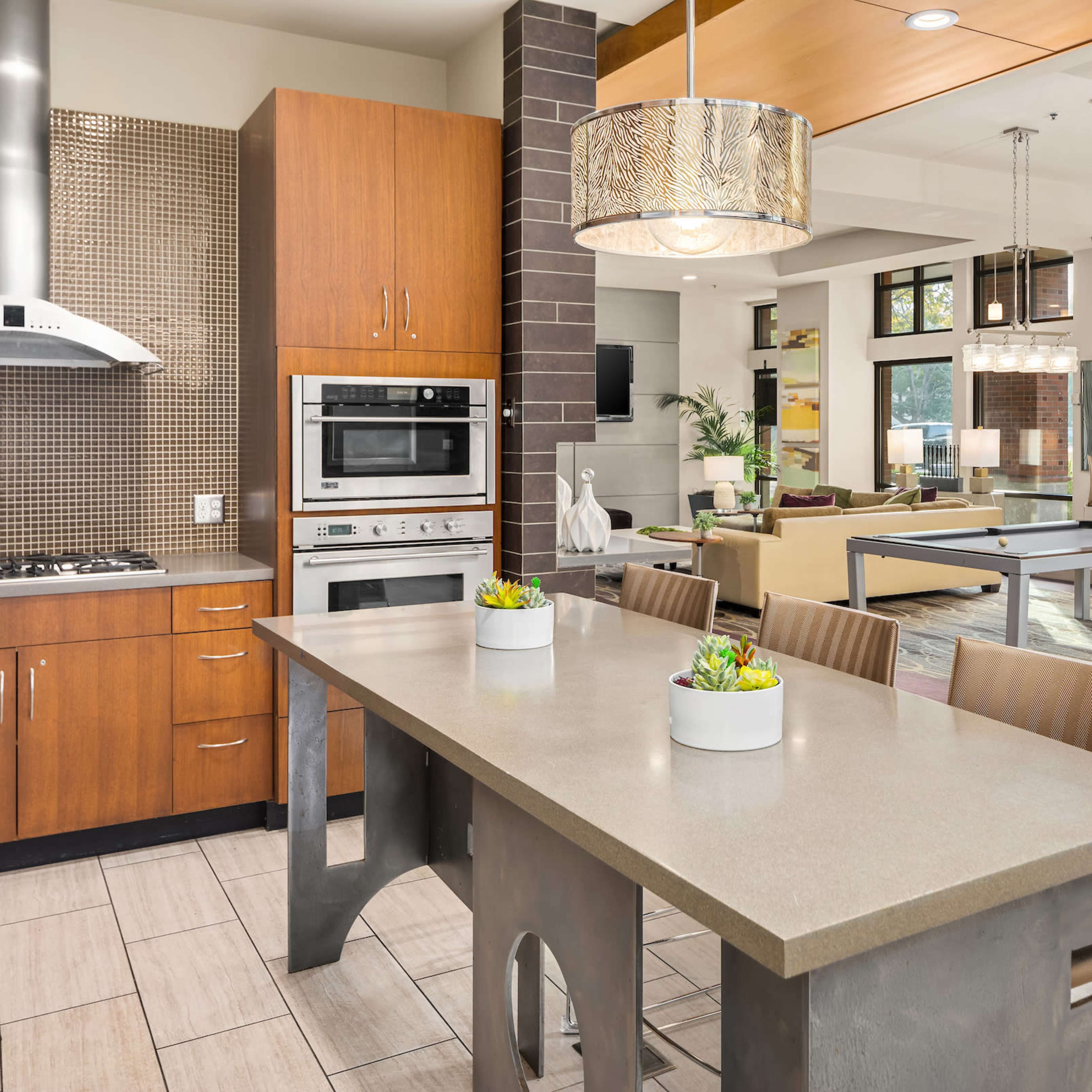 A modern kitchen featuring a central island with seating, stainless steel appliances, and a combination of wood and stone finishes.