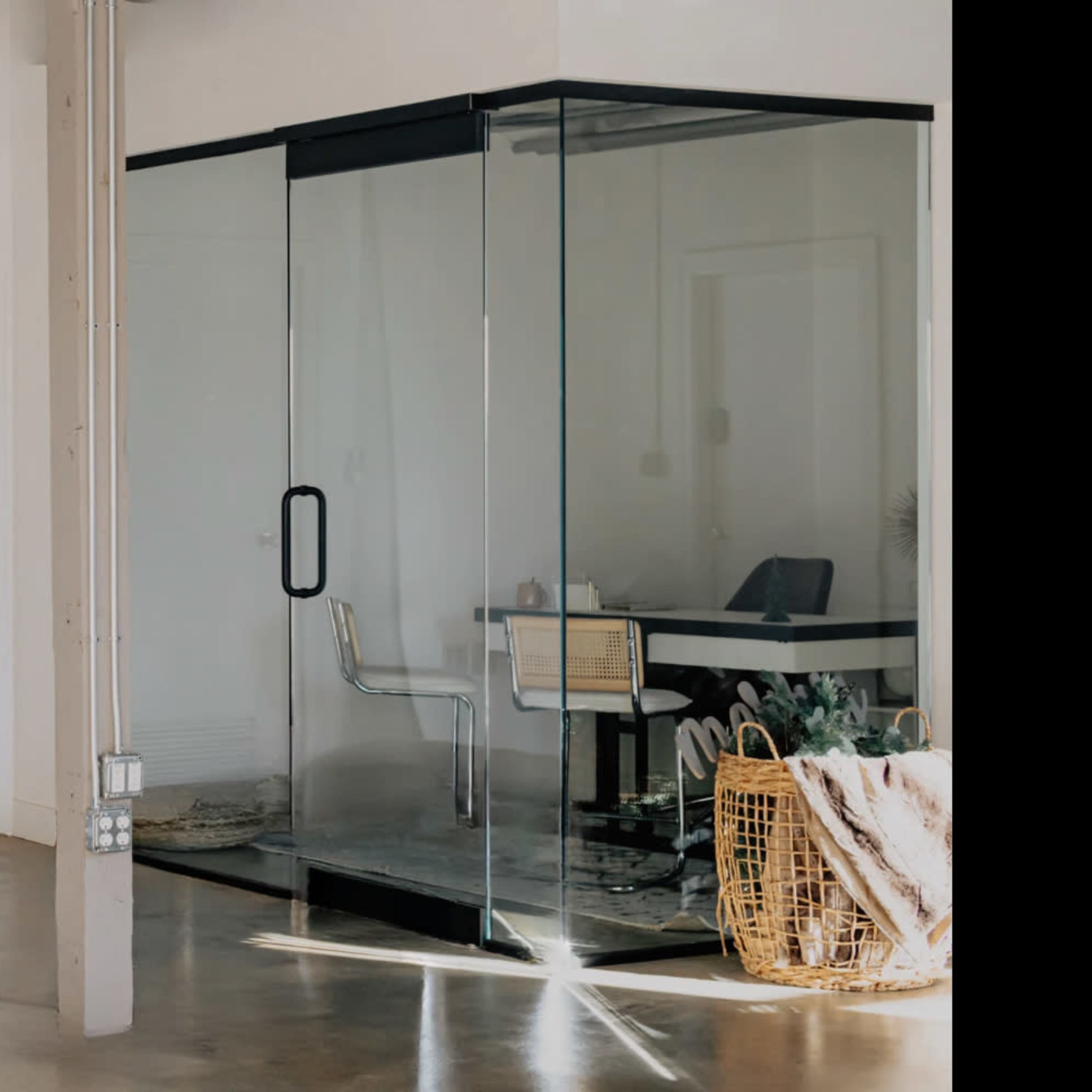 A photography studio with a black backdrop, a light stand, and a glass-enclosed workspace.