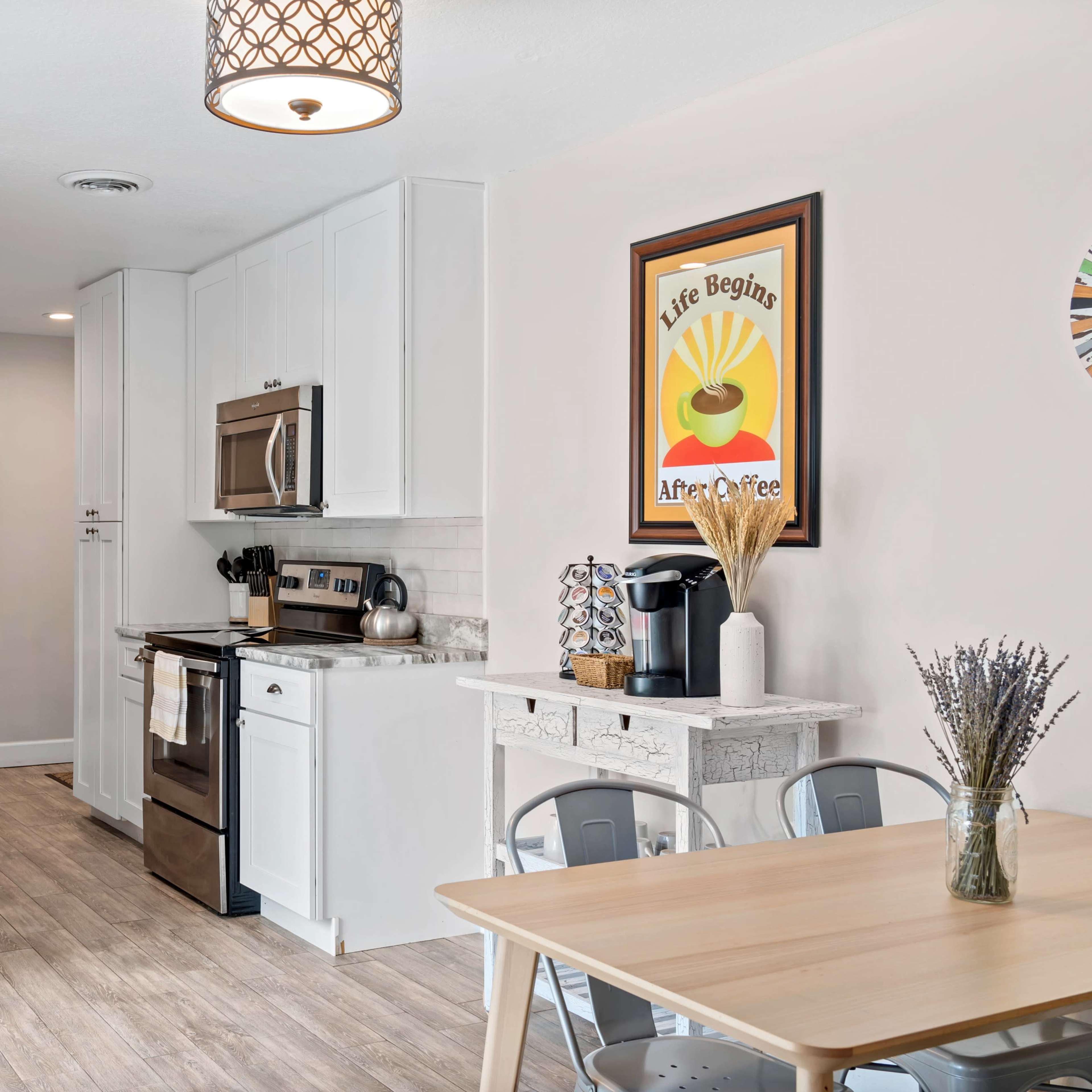 A modern kitchen with white cabinets, stainless steel appliances, and a wooden dining table set for four.